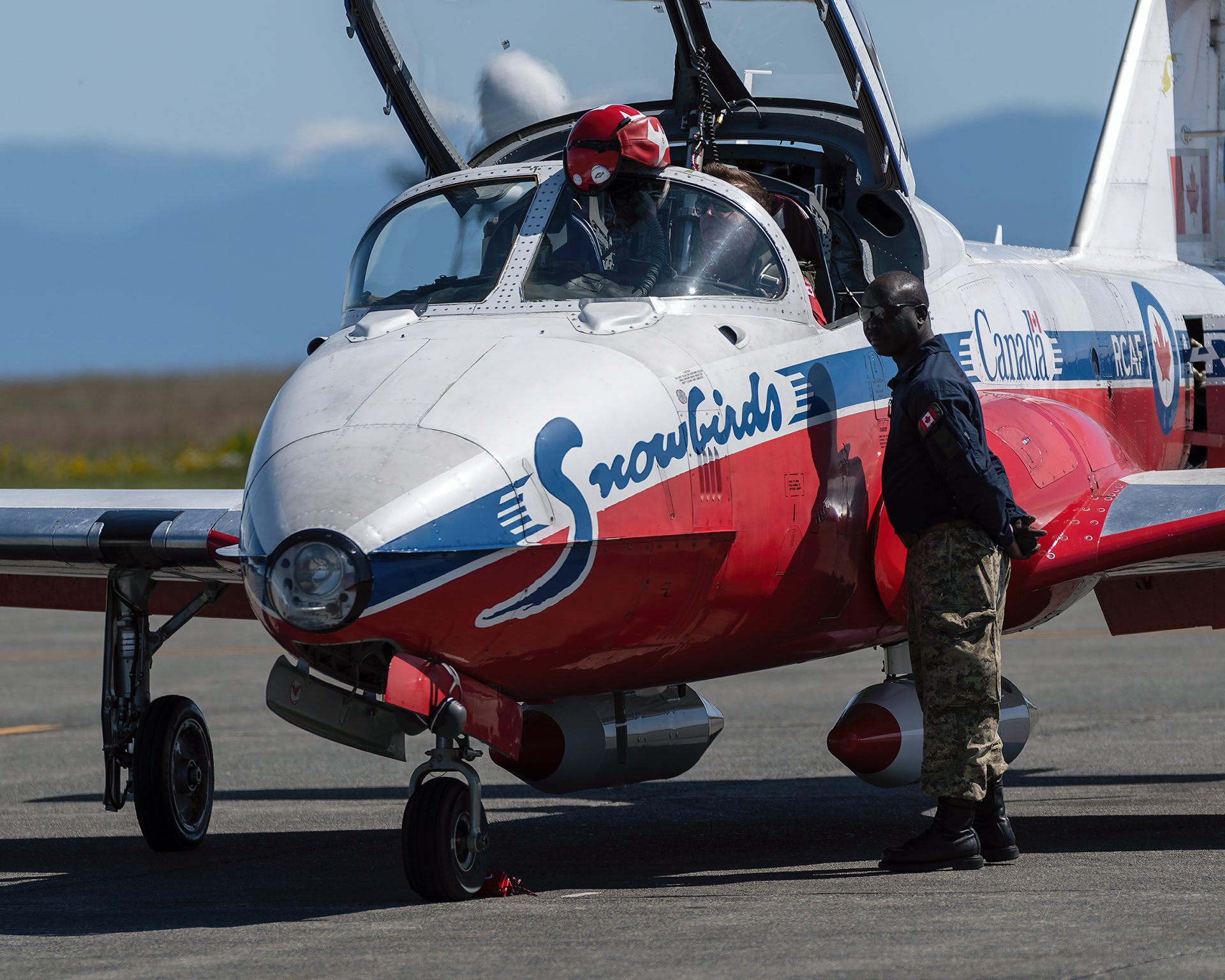 A Canadian Forces Snowbirds pilot confers with his crew chief technician on the flight line before a training mission during 2026 spring training at CFB Comox, British Columbia. Fine art aviation documentary photography by Kevin Prentice.
