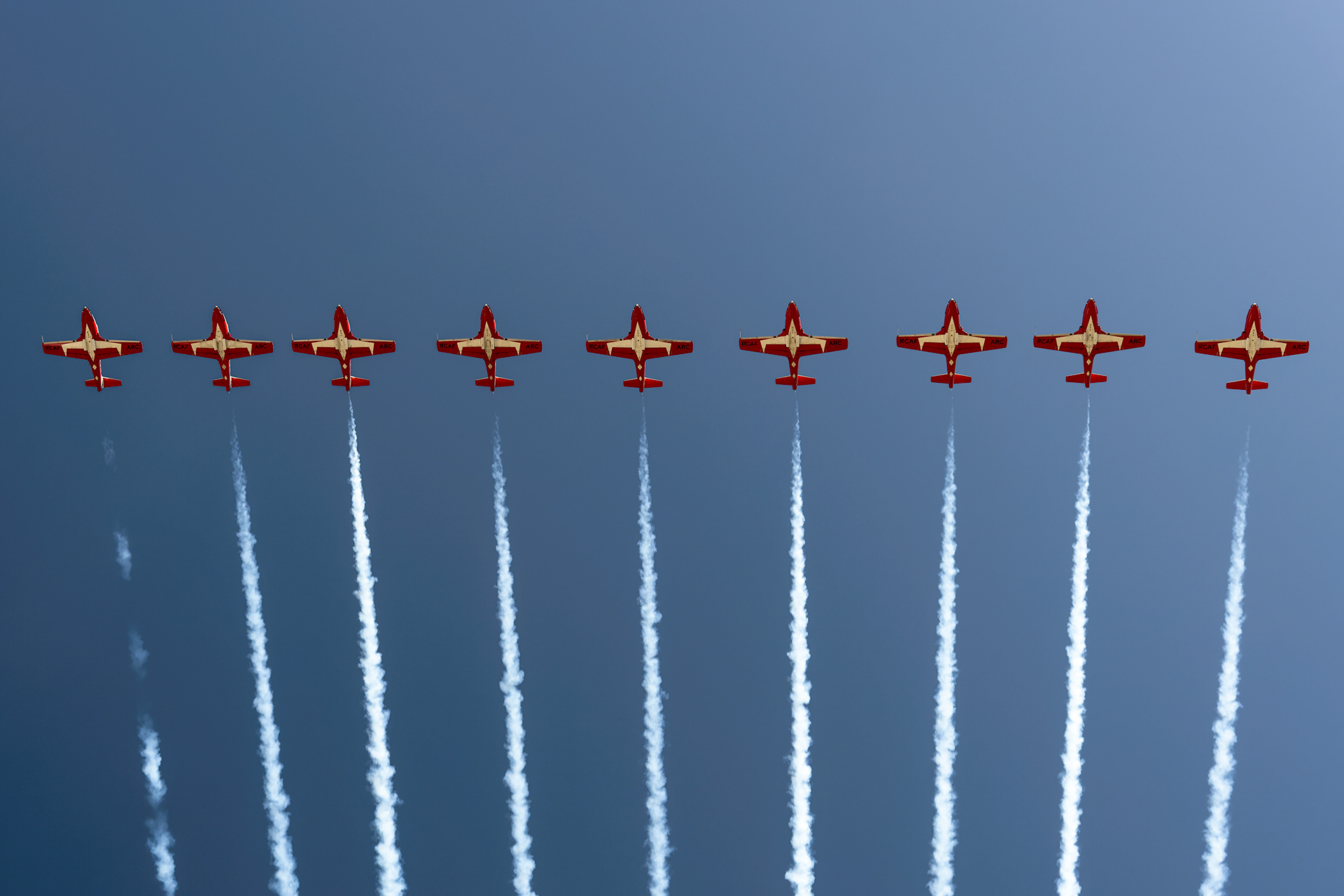 The Canadian Forces Snowbirds (431 Air Demonstration Squadron) perform a precision formation flight, leaving signature white smoke trails against a clear sky during their 2026 spring training demonstration over Vancouver Island. Fine art aviation photography by Kevin Prentice.