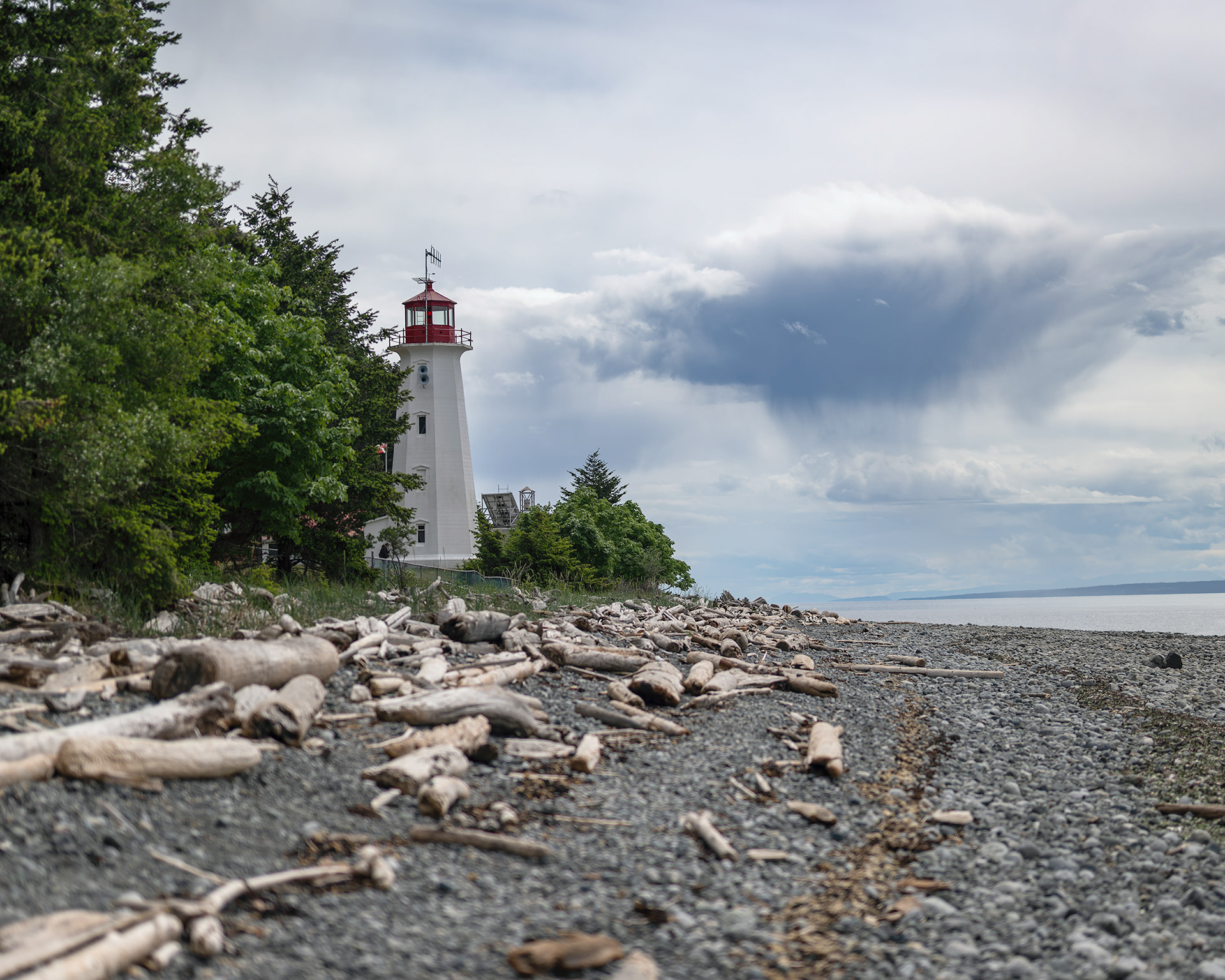 The historic Cape Mudge Lighthouse standing watch over the rugged, driftwood-lined shores of Quadra Island, British Columbia. Fine art coastal landscape photography by Kevin Prentice.