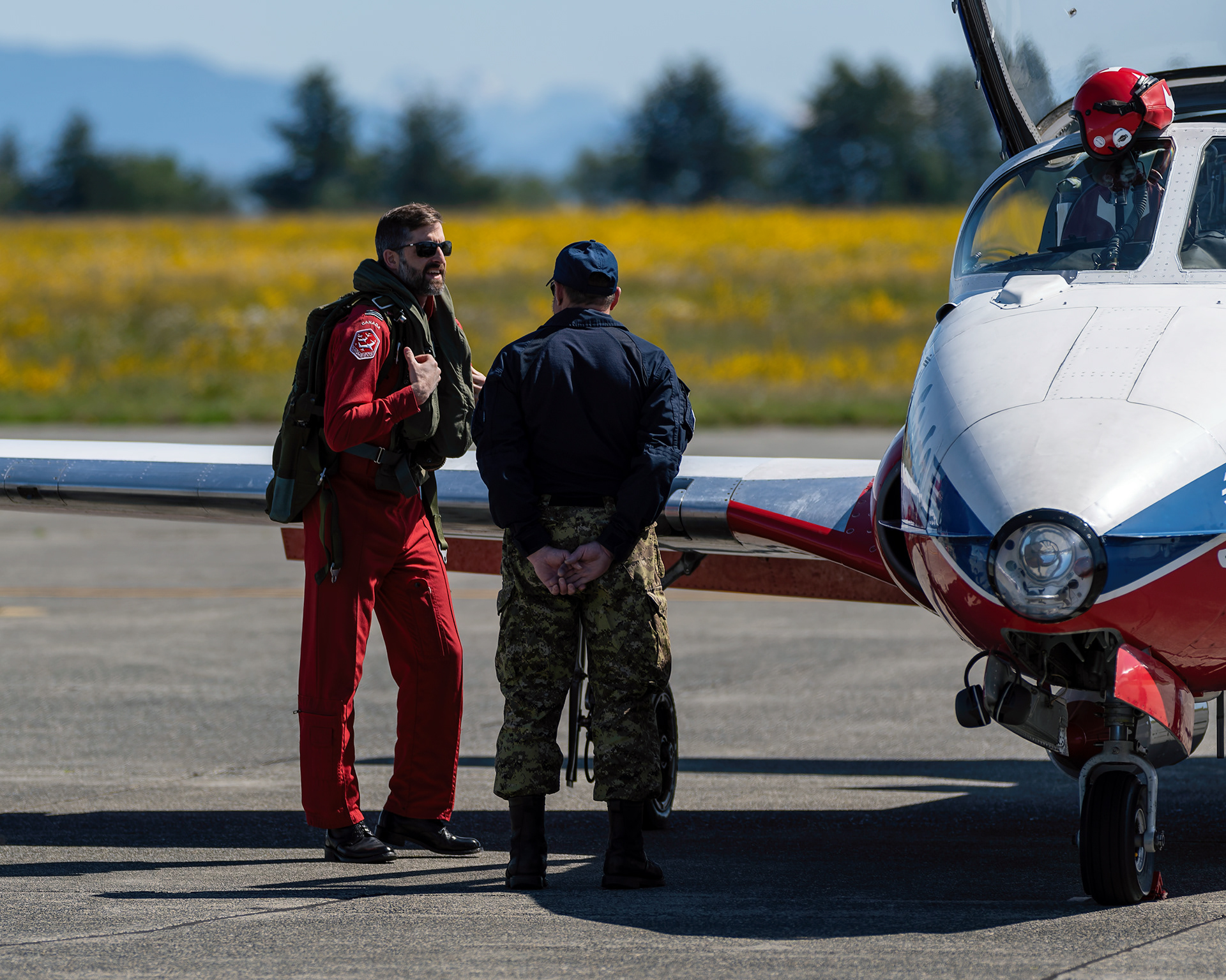 A Canadian Forces Snowbirds pilot confers with his crew chief technician on the flight line before a training mission during 2026 spring training at CFB Comox, British Columbia. Fine art aviation documentary photography by Kevin Prentice.