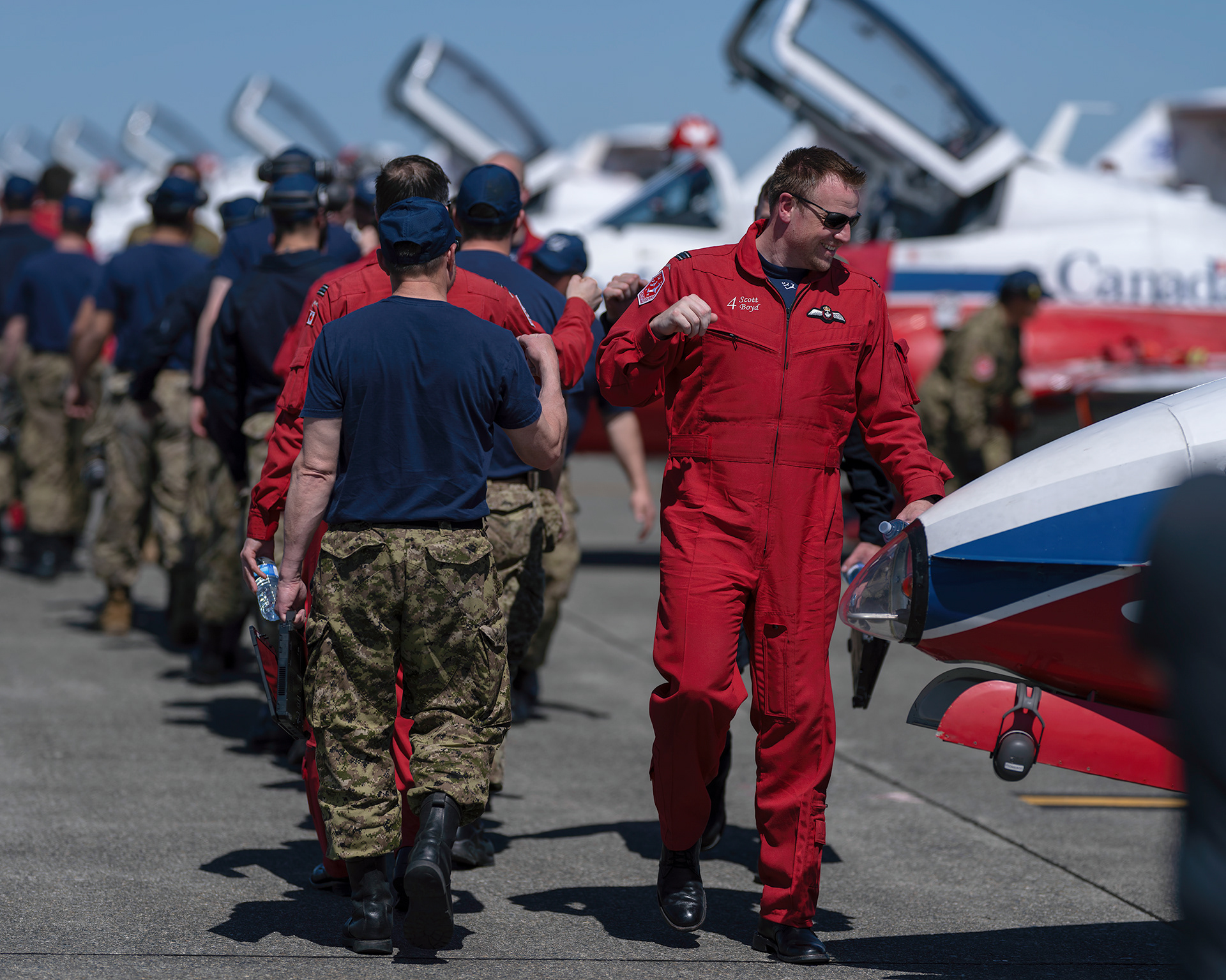 A Canadian Forces Snowbirds pilot shares a post-flight fist bump on the flight line during 2026 spring training at CFB Comox, British Columbia. Fine art aviation lifestyle photography by Kevin Prentice.
