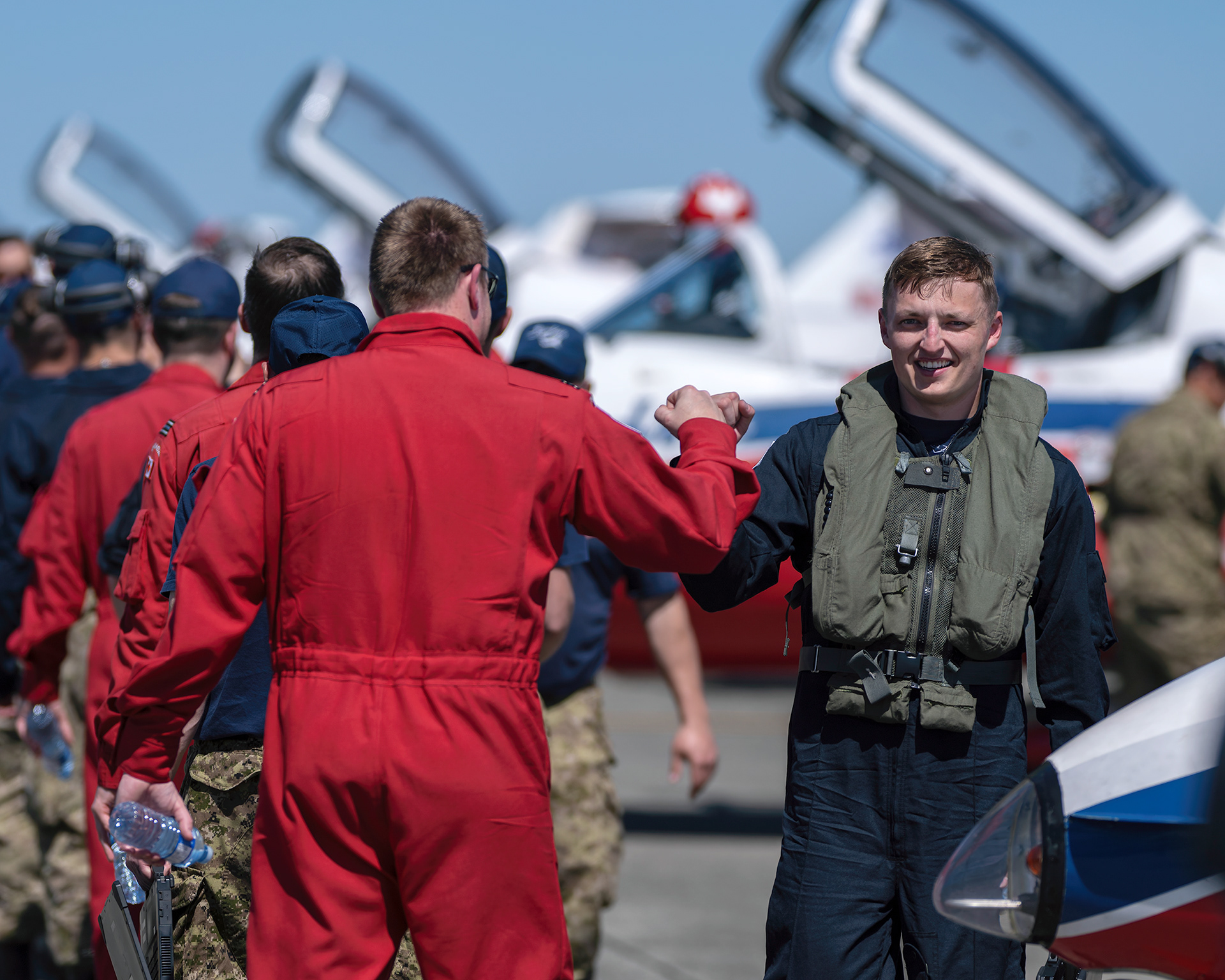 A Canadian Forces Snowbirds pilot and crew member share a post-flight fist bump on the flight line after a successful practice flight during 2026 spring training at CFB Comox, British Columbia. Fine art aviation lifestyle photography by Kevin Prentice.