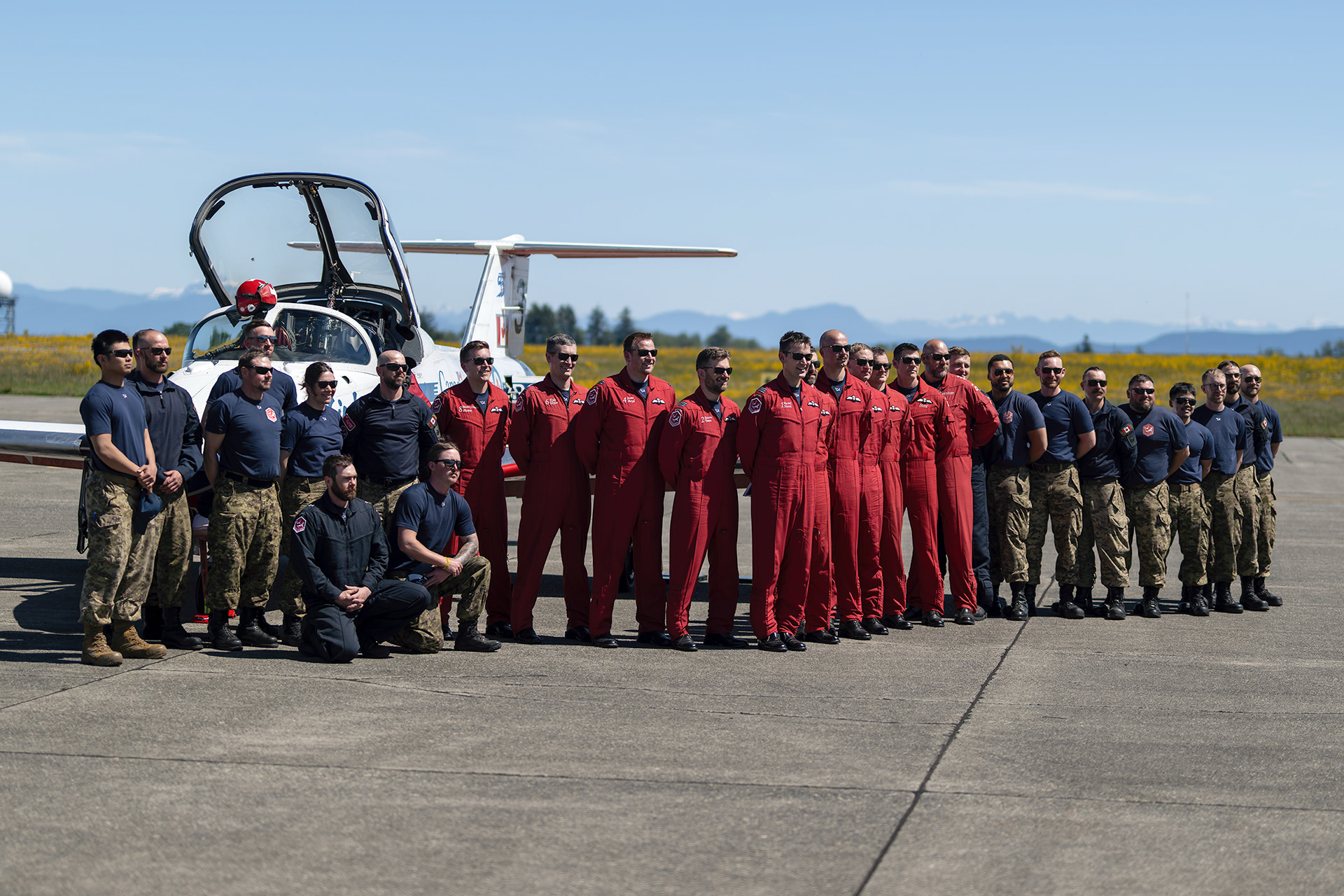 The Canadian Forces Snowbirds pilots, technicians, and support personnel of the 431 Air Demonstration Squadron gather for a team portrait during their 55th anniversary spring training deployment at CFB Comox, British Columbia. Fine art aviation documentary photography by Kevin Prentice.