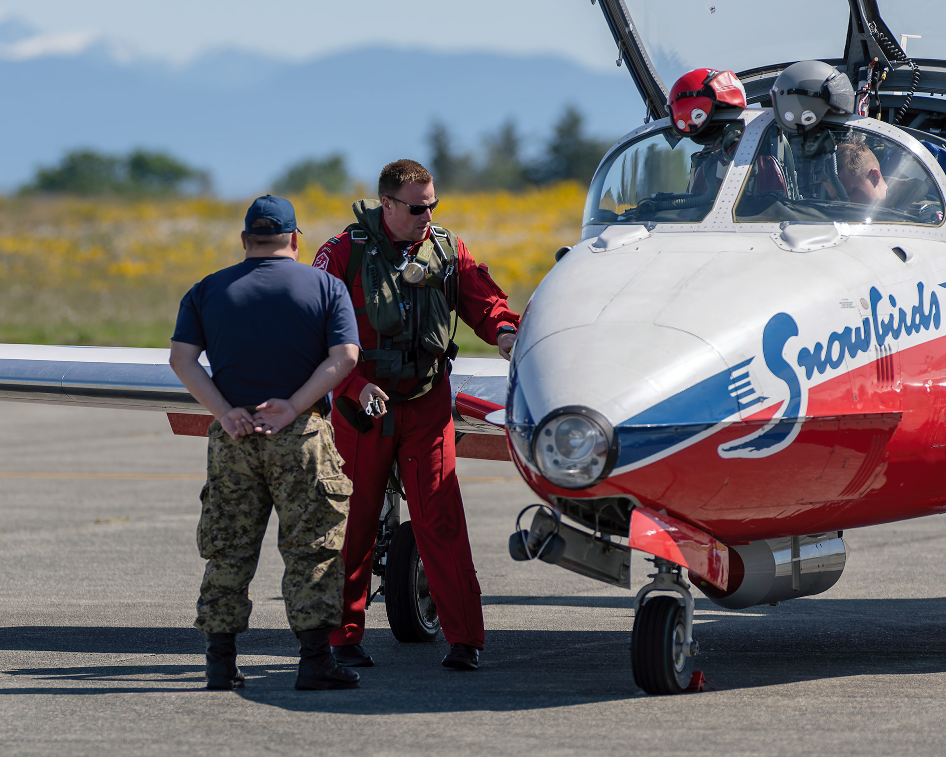 A Canadian Forces Snowbirds pilot confers with his crew chief technician on the flight line before a training mission during 2026 spring training at CFB Comox, British Columbia. Fine art aviation documentary photography by Kevin Prentice.