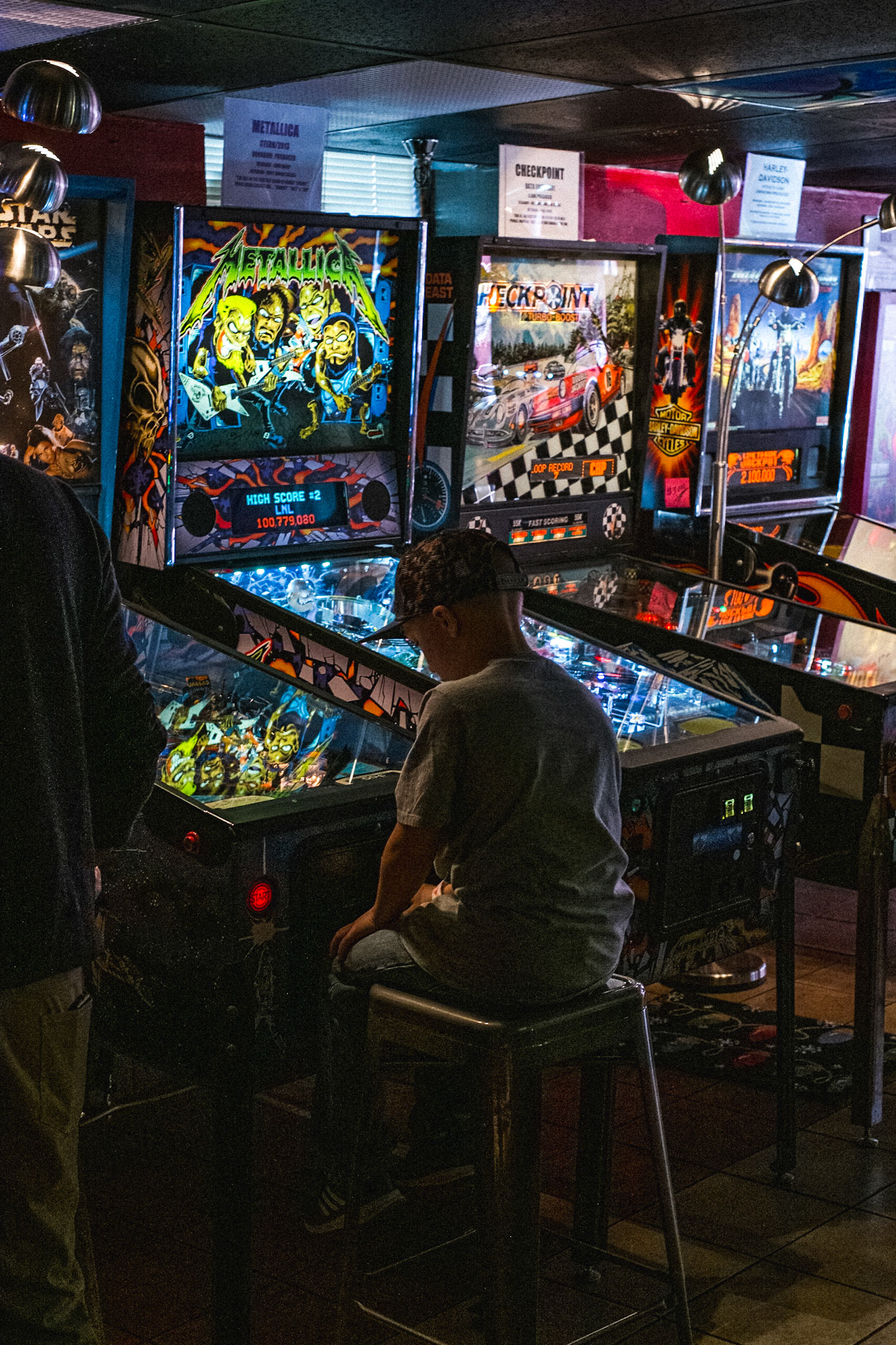 (Mostly) Bicycling America XXVI. A Boy Sits at a Pinball Machine at the Asheville Pinball Museum in Asheville, North Carolina, November, 2016. I was on the last few days of my drive home from the west coast and wanted to make a short stop in Asheville, as I'd heard it's a great little town up in the Appalachian mountains. Also, as I researched it I discovered it contained a great little pinball arcade/museum! As part of the purpose in traveling around the United States is to unearth and discover what is America, and I already had some ideas about what America was, or what was emblematic of America, pinball machines and arcades definitely made the list, as they are, in my opinion, quintissentialy American, and to quite a large extent are a part of America that is nearly extinct. But in a few towns and cities around the country one can find people preserving these bastions of fun and sanity for the nostalgia of an older generation to revisit, and for a younger generation to become acquainted to and learn about, as evidenced in this photograph. The Asheville Pinball Museum executes this idea perfectly.