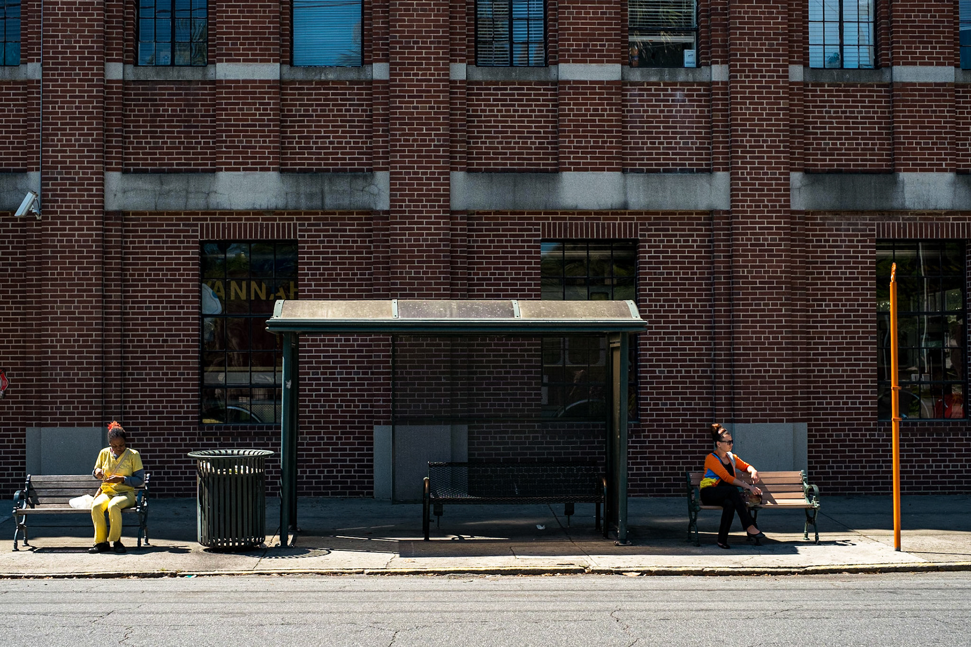 (Mostly) Bicycling America XXIII. Two Women at a Bus Stop, Savannah, GA, April, 2016. I posted a black &amp; white version of this photograph ages ago, but I think it bares re-posting what with all the turmoil, pain, anguish, and suffering we've all seen this year. Obviously I don't know whether these two women sat like this intentionally. Maybe they both just wanted to be in the sun, and not in the shade of the bus stall, and aside from sitting side by side on the same small bench there was no way to do this other than in the manner shown. I have no idea. All I know was that I was walking along on the opposite side of the street and knew I had to take the picture. It's too emblematic of this country's past, and sadly, its present. Whenever I look at this photo I think of a part of a recording of a sermon that M.L.K. gave that is played at the beginning of a song by the hardcore band Good Riddance: "Modern man suffers from a kind of poverty of the spirit, which stands in glaring contrast to his scientific and technological abundance. We've learned to fly the air like birds, we've learned to swim the seas like fish. And yet we haven't learned to walk the Earth like brothers and sisters."