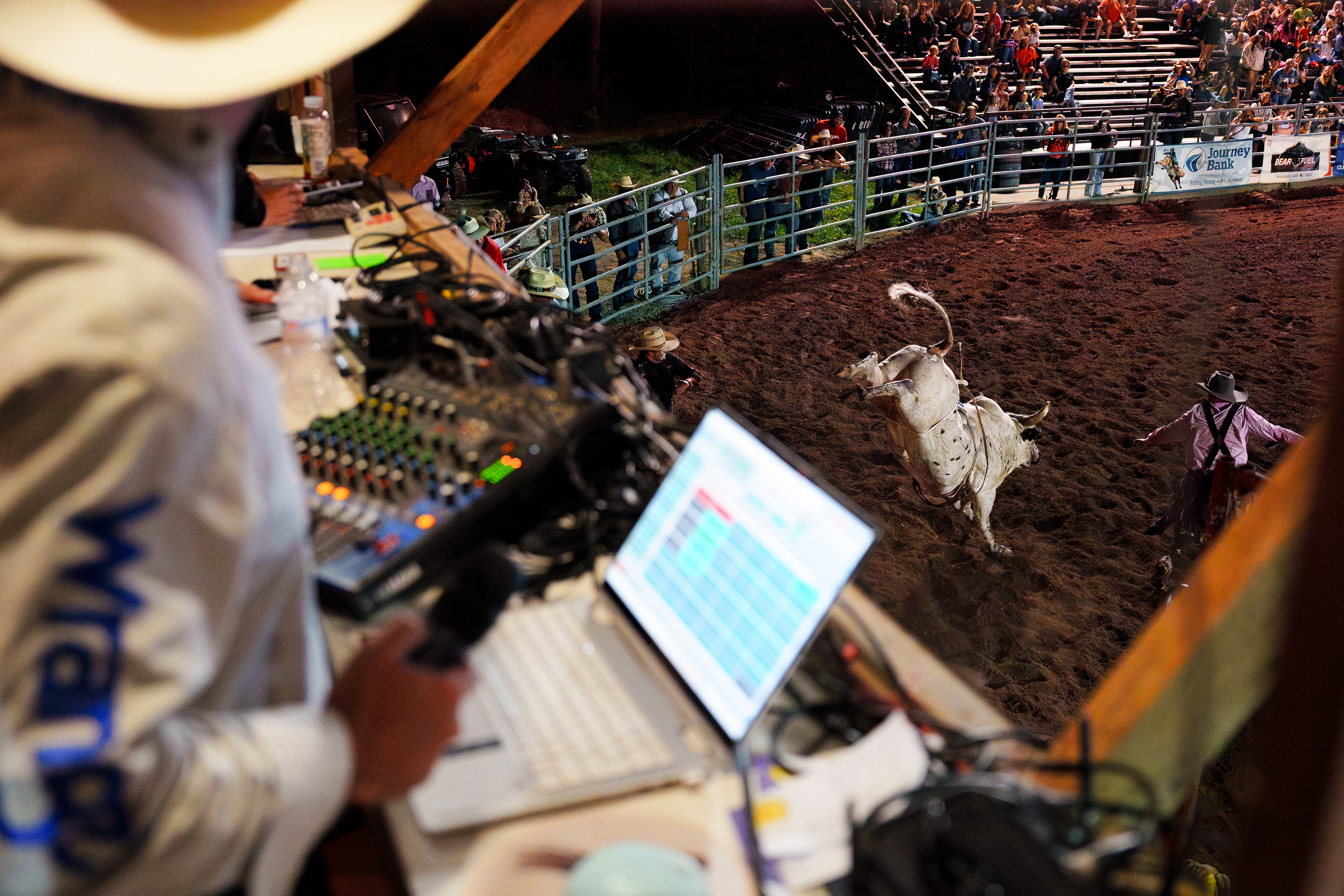 The rodeo announcer watches the arena from the announcer’s booth as a bull bucks during the Benton Frontier Days Rodeo in Benton, Pa.