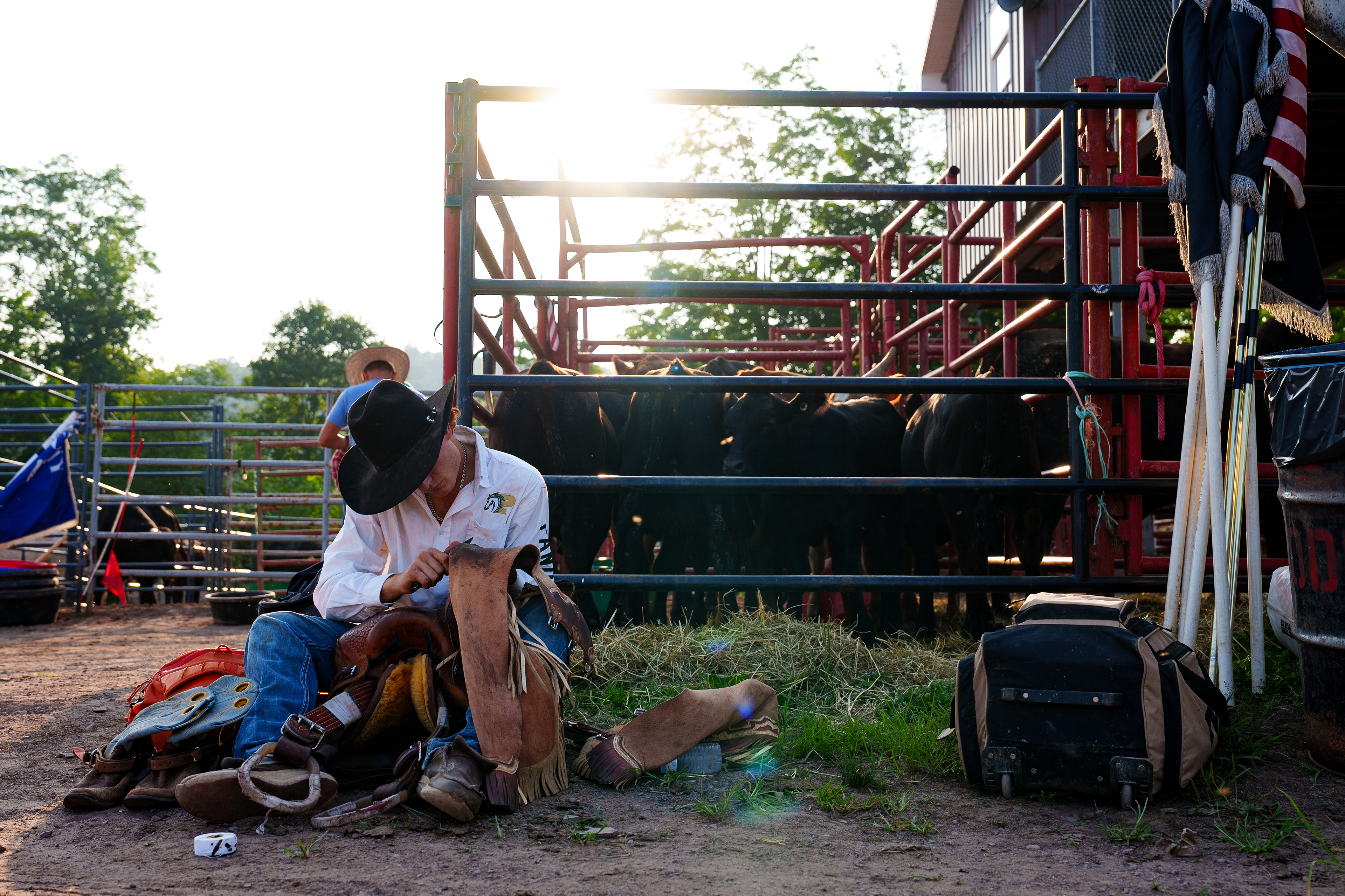 Tyler Wall scrapes one of his leather chaps with a knife while preparing to compete at the Benton Frontier Days Rodeo in Benton, Pa. 