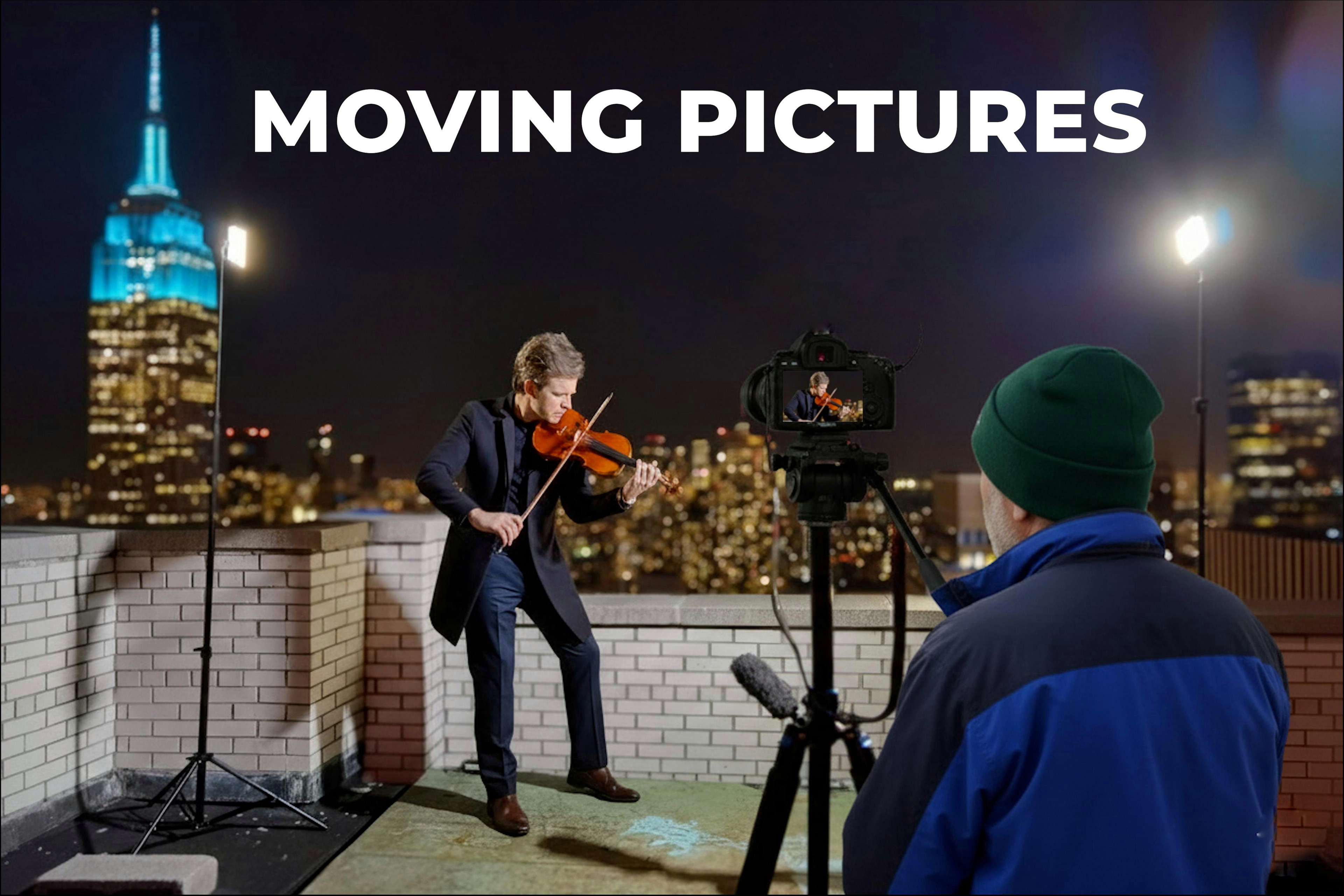 A violinist being filmed on a New York rooftop with the Empire State Building in the background