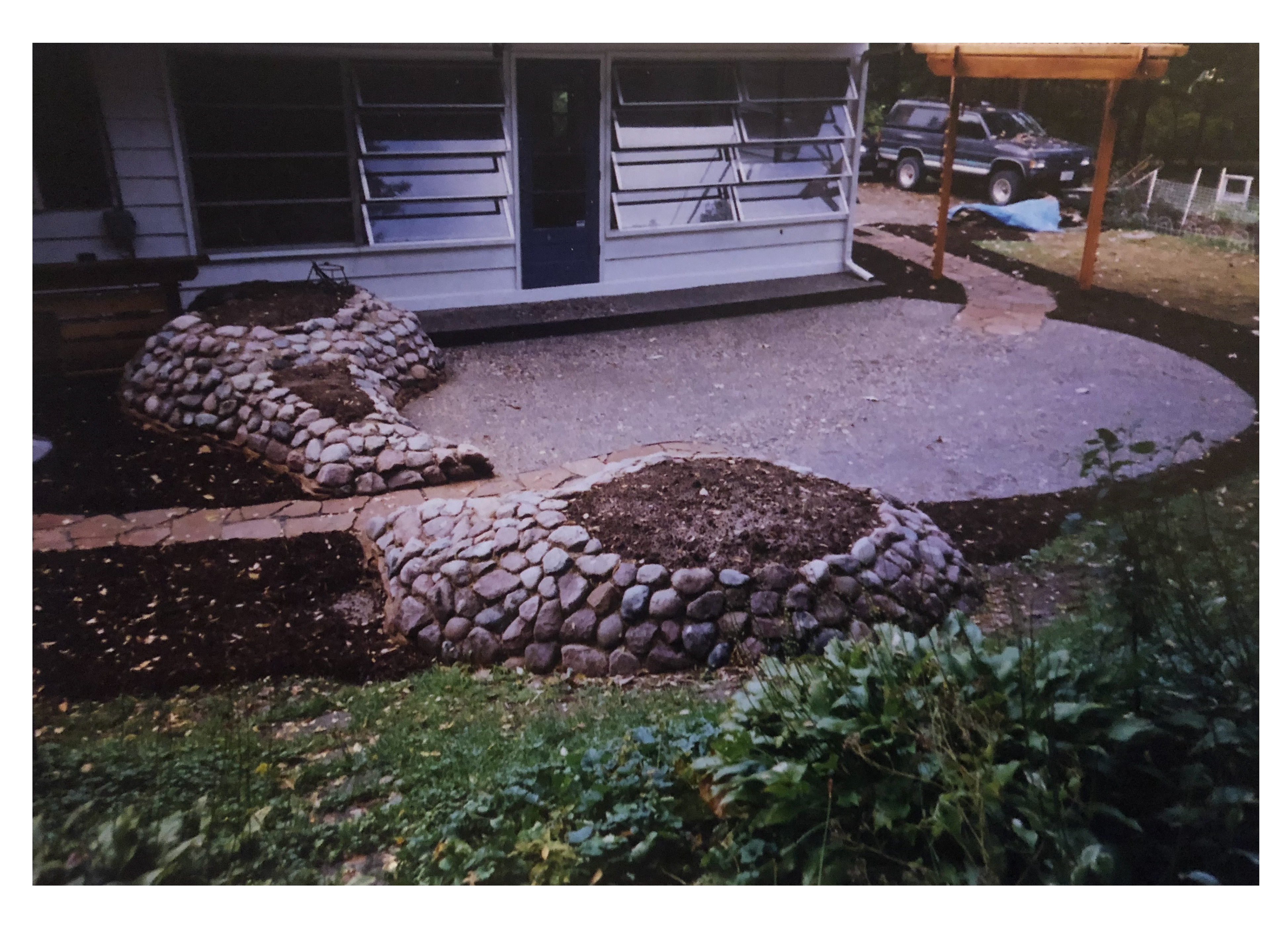 Two annual planters along a nexposed agregate patio.