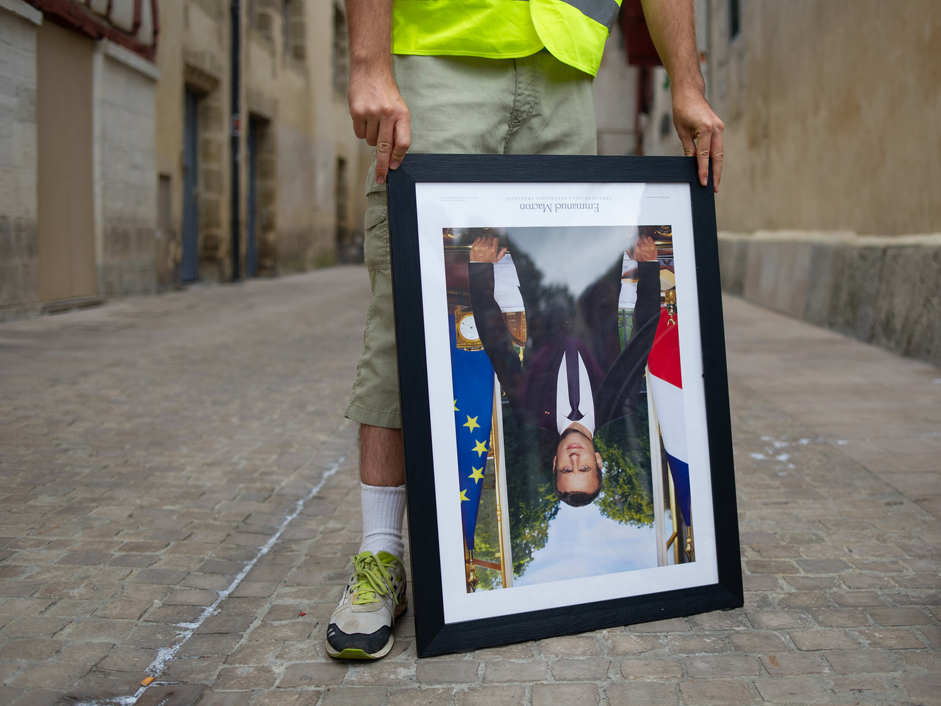A demonstrator poses for a photo with a portrait of president Emmanuel Macron head-down during the march of portraits on the second day of G7 summit on August 25, 2019 in Bayonne, France.