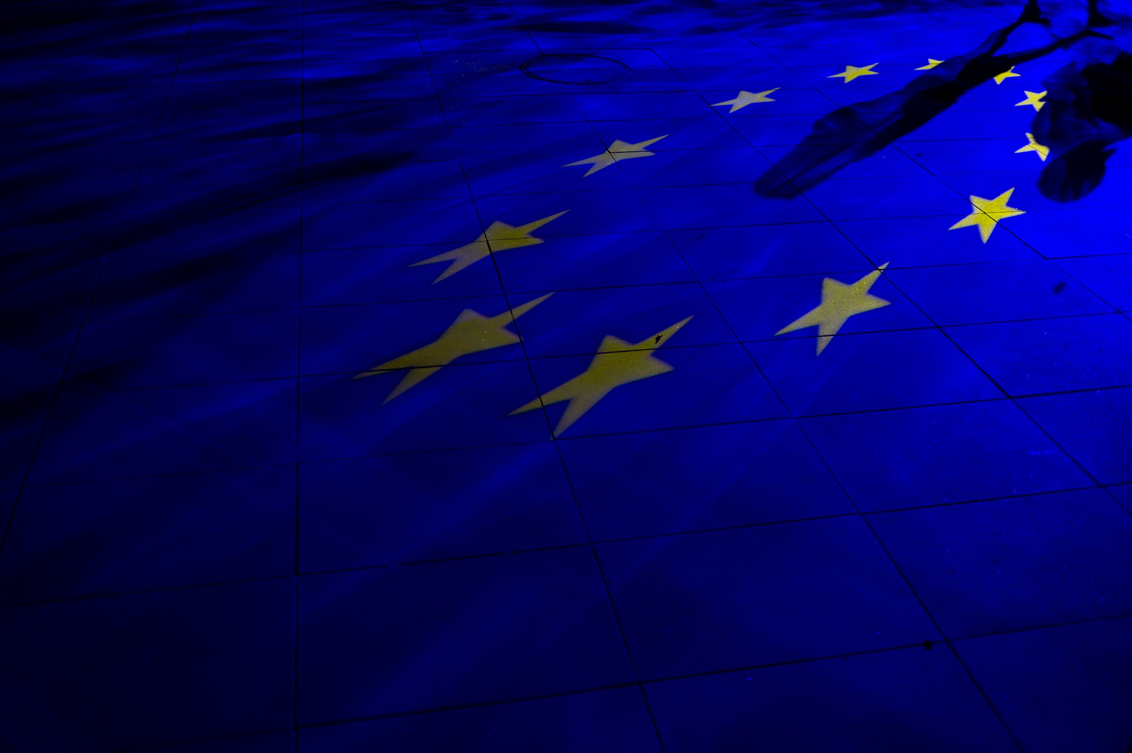 People walk past the European Union flag projected on the floor in Warsaw, Poland on April 30, 2019. The 1 of May 2019 marks the 15th anniversary of Poland joining the European Community.