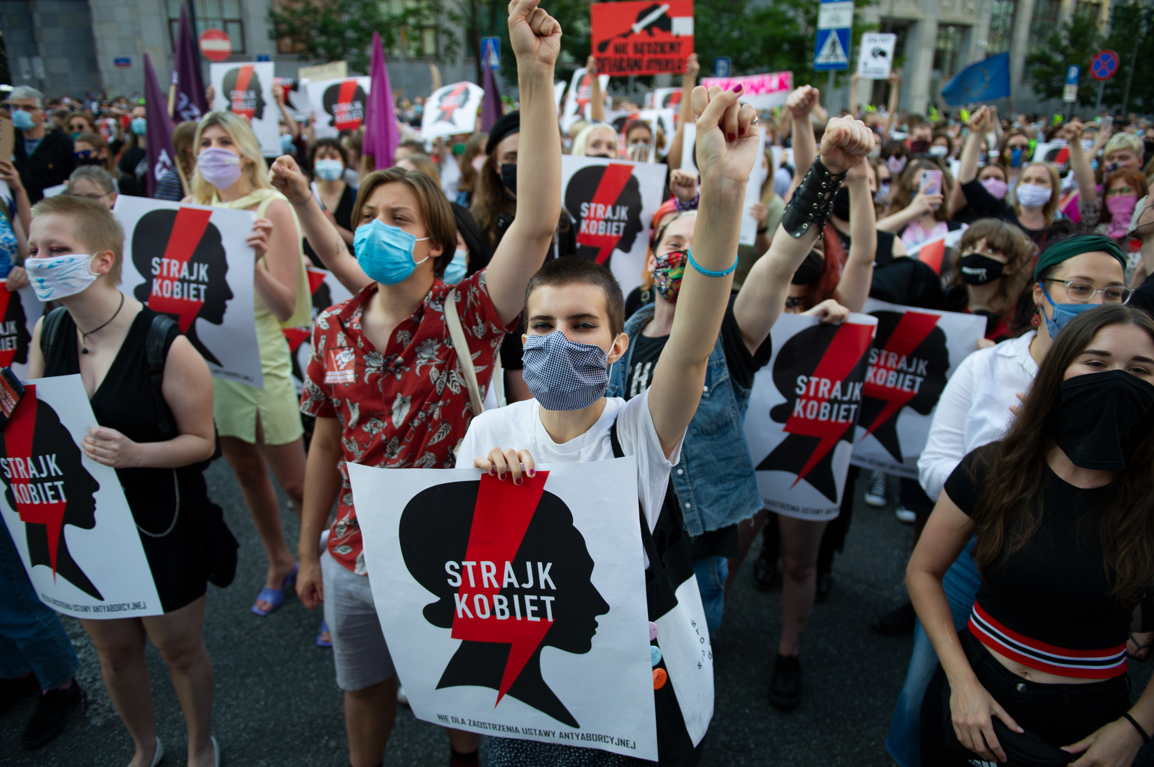 Demonstrators wearing protective face masks rise their fist during an anti-domestic violence protest on July 24, 2020 in Warsaw, Poland. Thousands of demonstrators took part in a protest against government plan to pull out of an international treaty on preventing and combating domestic violence.