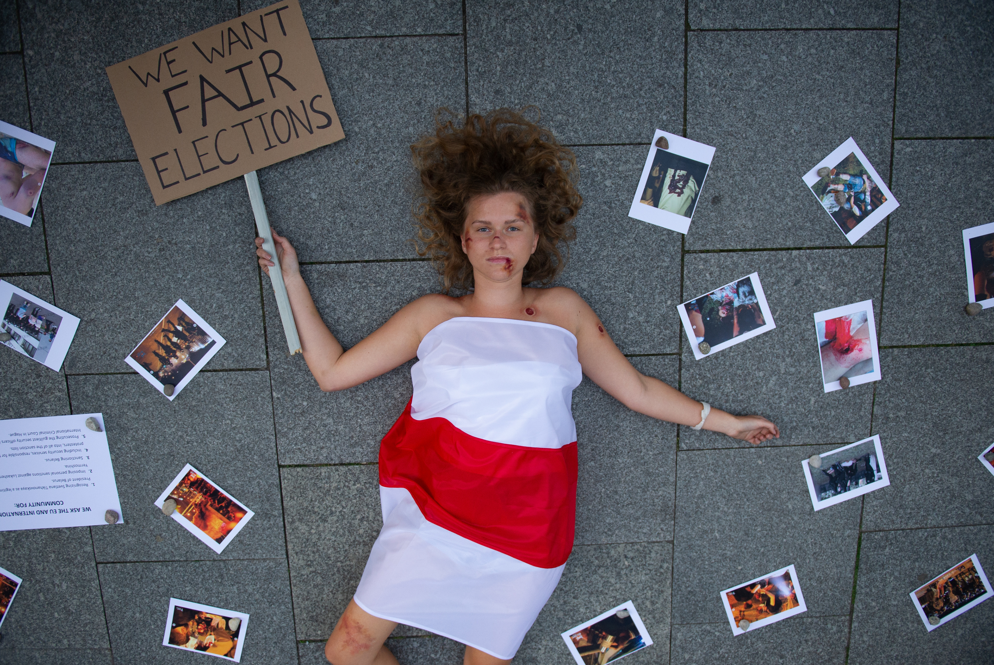 A demonstrator wrapped in a Belarusian flag takes part in a die-in performance in front of the European Commission (EC) building on August 13, 2020 in Warsaw, Poland