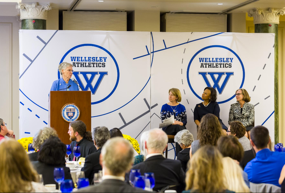 an inductee speaks in front of designed backdrop
