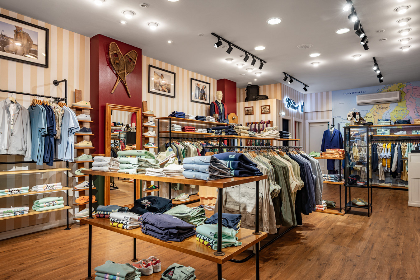 Interior de tienda de moda con exposición de prendas, calzado y mobiliario de madera