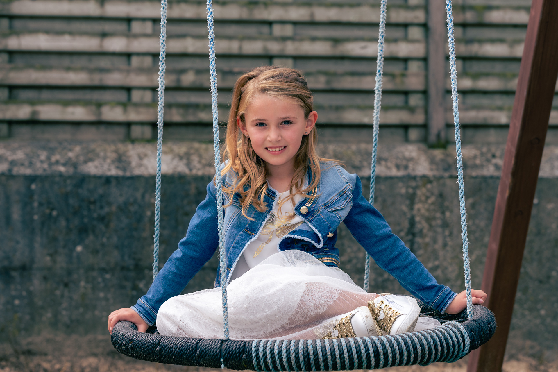 Meisje op schommel in communiekledij