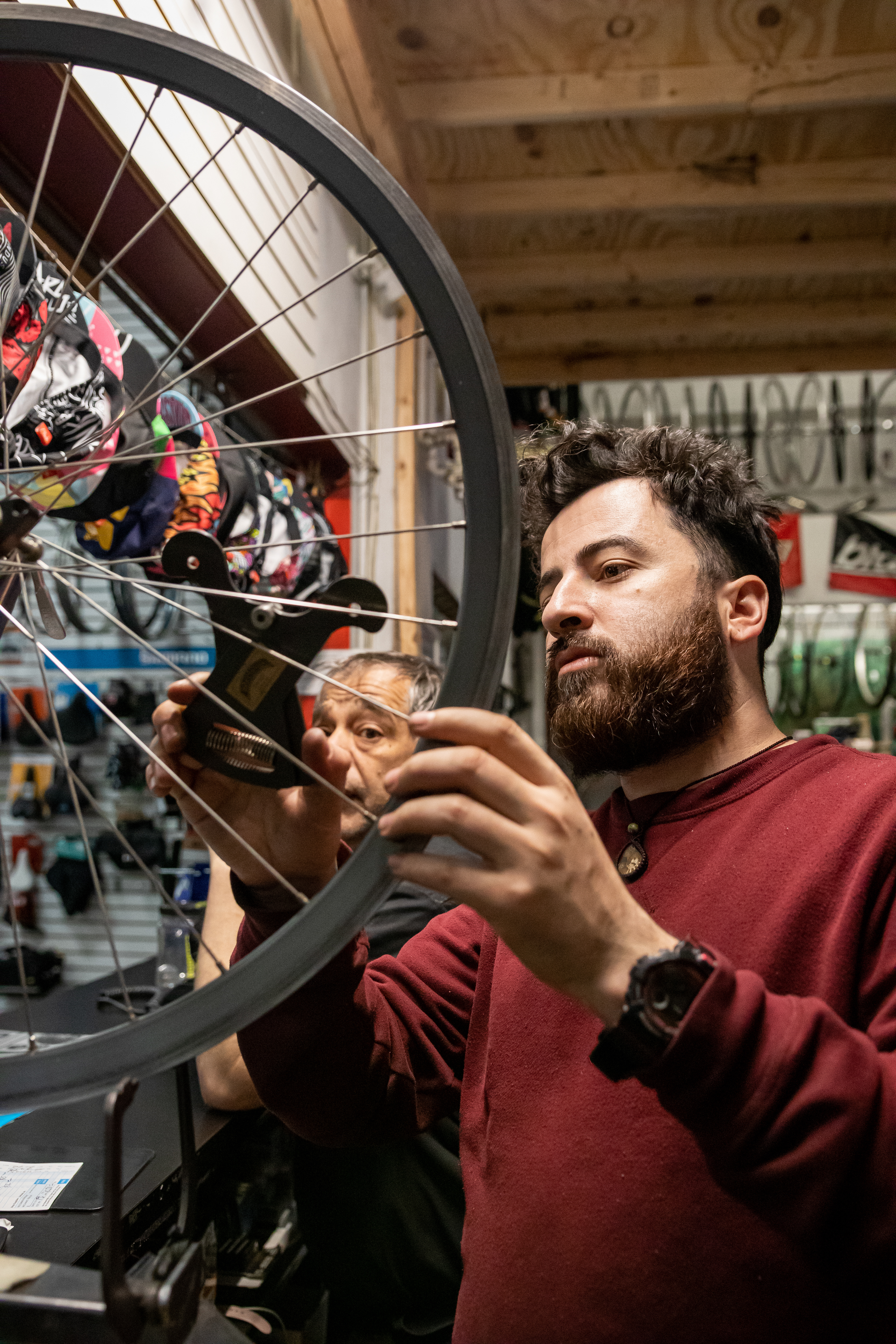 Mechanic Fabian Gil demonstrates an obsolete tool used to measure spoke tension, April 15, 2022 at Community Bike Supply, Boston, Massachusetts. Gil learned to build wheels from some of the most experienced wheel builders in the business, according to himself (Ryan Li).