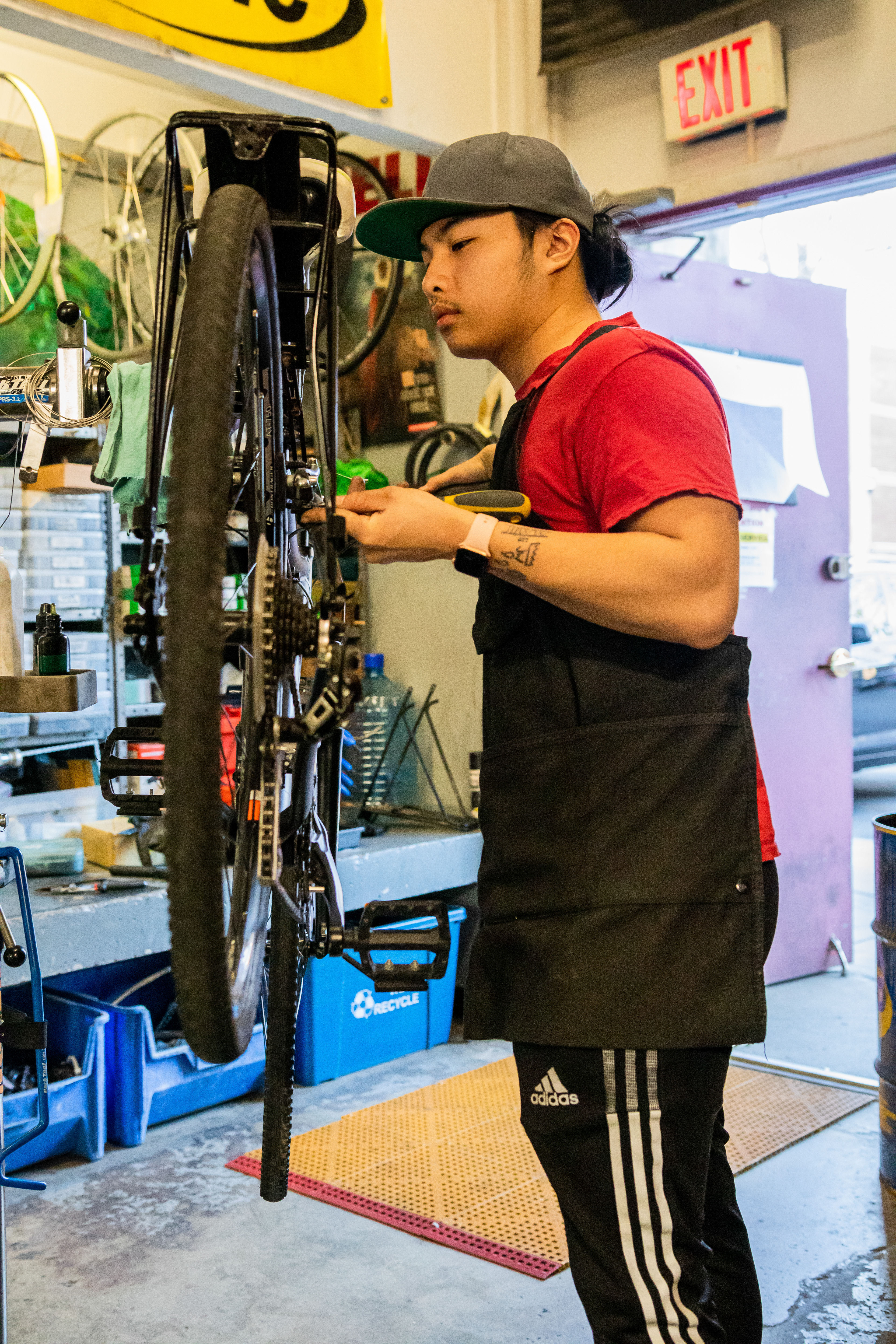 Mechanic Andy Qiu adjusts the brakes on a customer's bike, April 15, 2022 at Community Bike Supply, Boston, Massachusetts. Qiu works two jobs: as a mechanic at Community Bike Supply and as a retail associate in Boston Logan Airport, but said he enjoyed being a mechanic significantly more (Ryan Li).