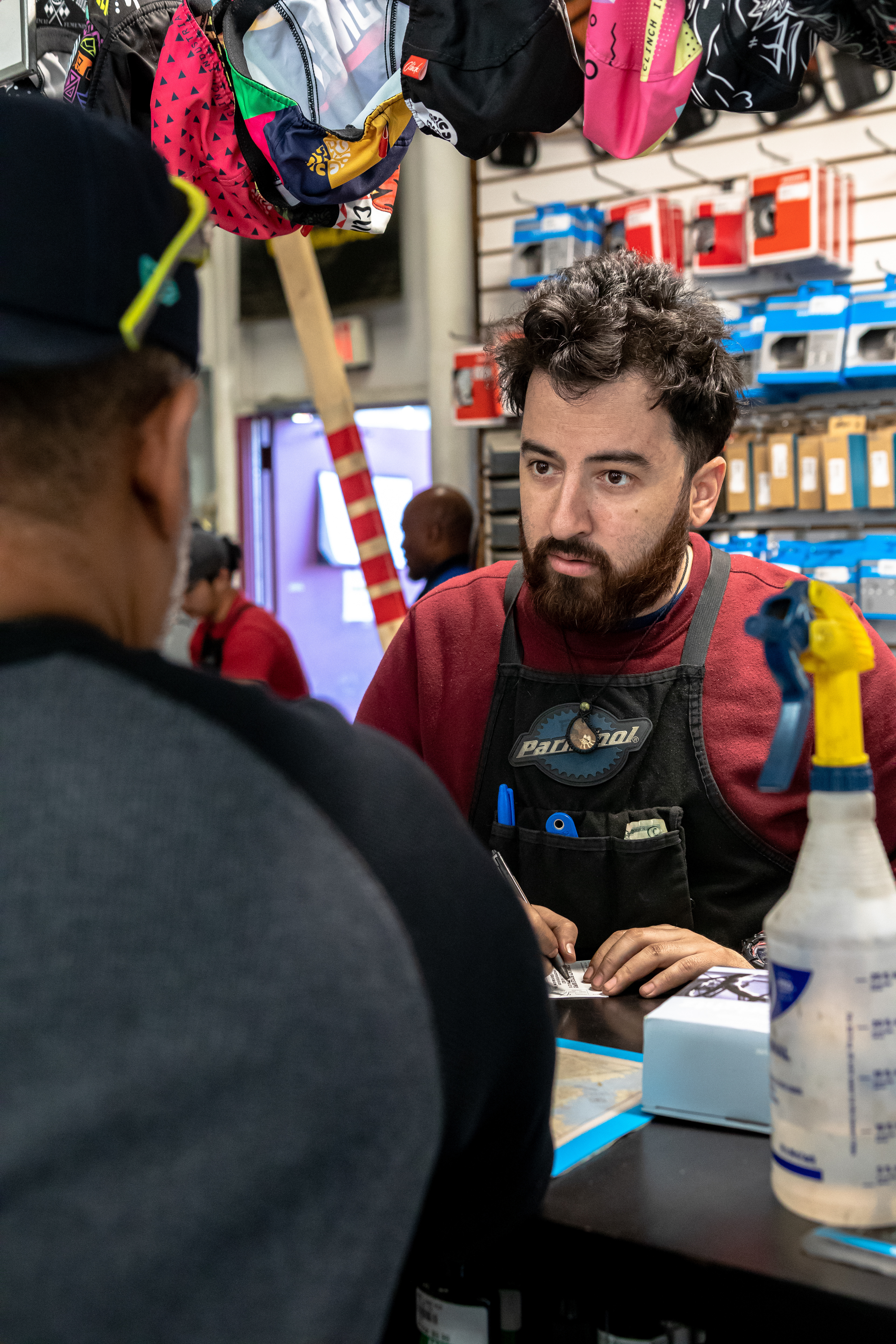Mechanic Fabian Gil records a repair order for a customer on April 15, 2022 at Community Bike Supply, Boston, Massachusetts. Gil can be found behind the rear counter doing everything from taking customer repairs and orders to completing tune-ups to restocking inventory (Ryan Li).