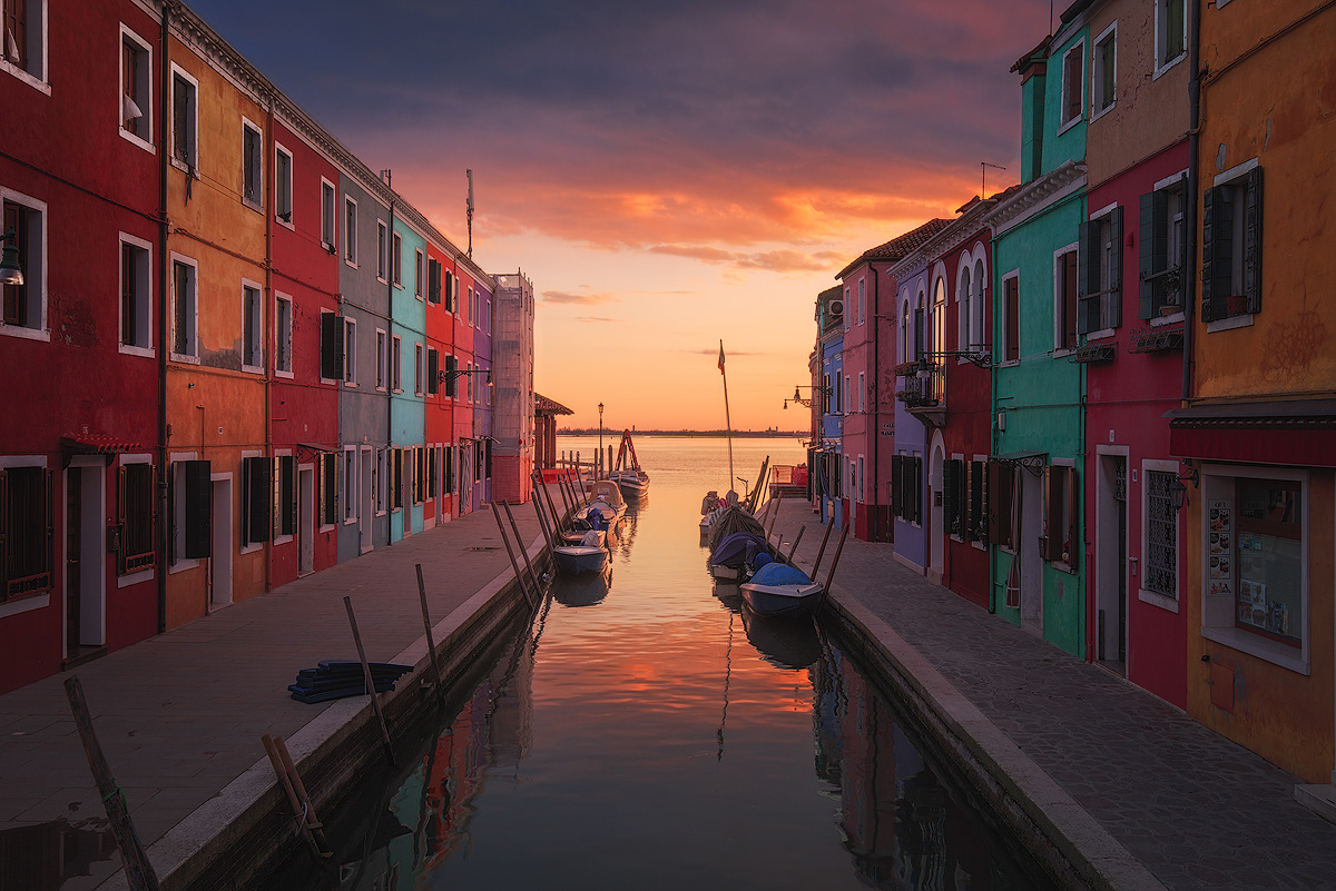 Canale di Burano al tramonto con case colorate e barche
