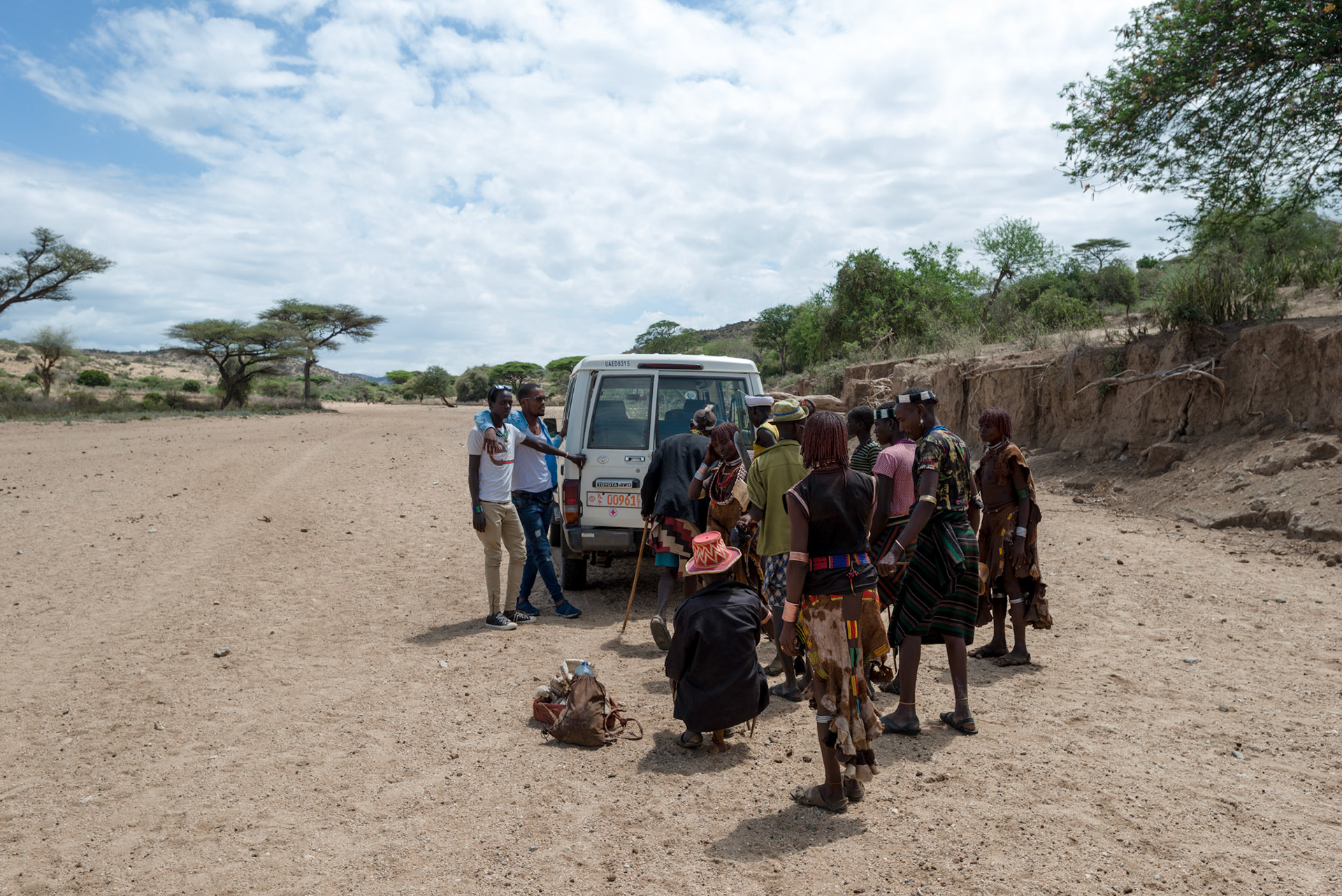 Hamer people gather for the moringa plant distribution in a dry river bed,