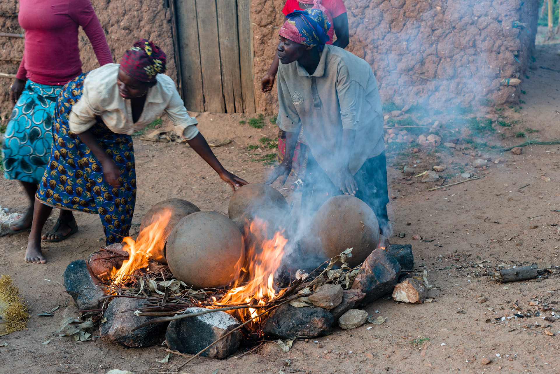 Philomene firing the pots she made this day. The pots are placed on a fire and covered with dry and green grass. Firing takes about an hour.
These pots were once used by everyone to store water and cook food, but they have been rapidly replaced by metal and plastic.