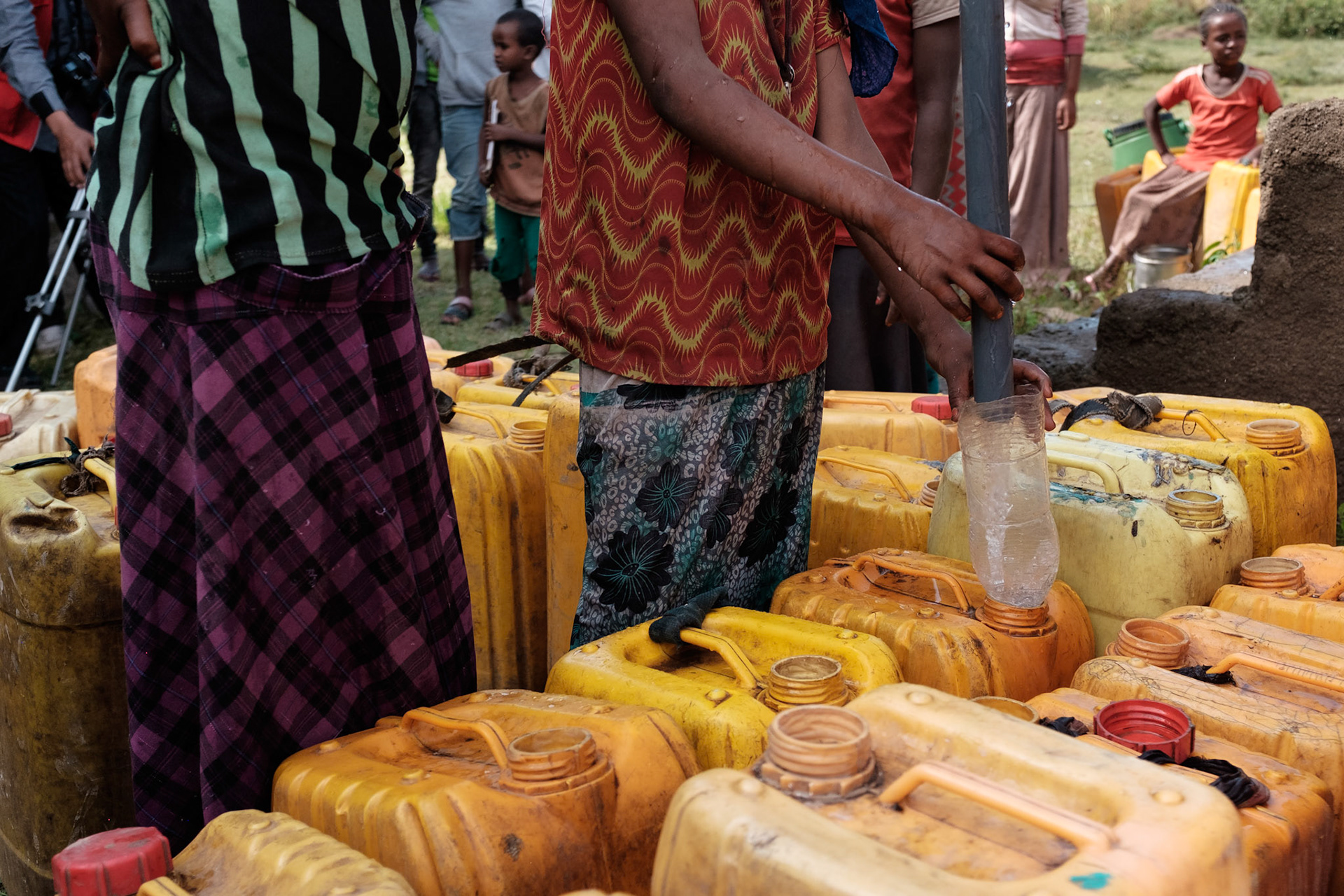 Women and children filling water cans from the Austrian Red Cross water tank.
The water tank collects rain water from the roof of the adjacent building. This water point saves the local people much time in collecting water.