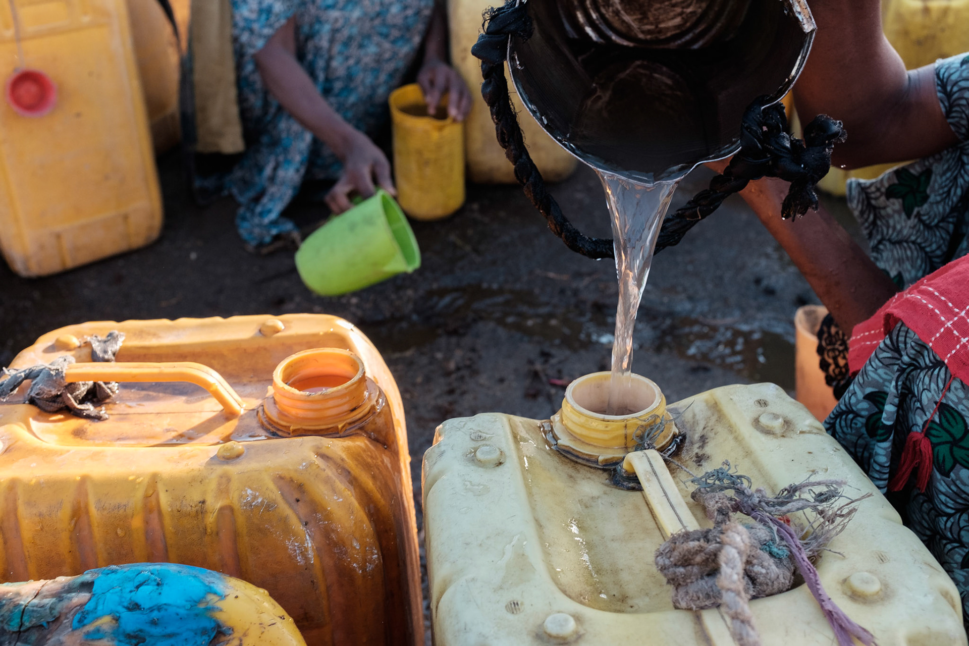 When there is no easily accessible clean water source, women are forced to collect water where it can be found. These women in the Shalla region are collecting water running down a road.
