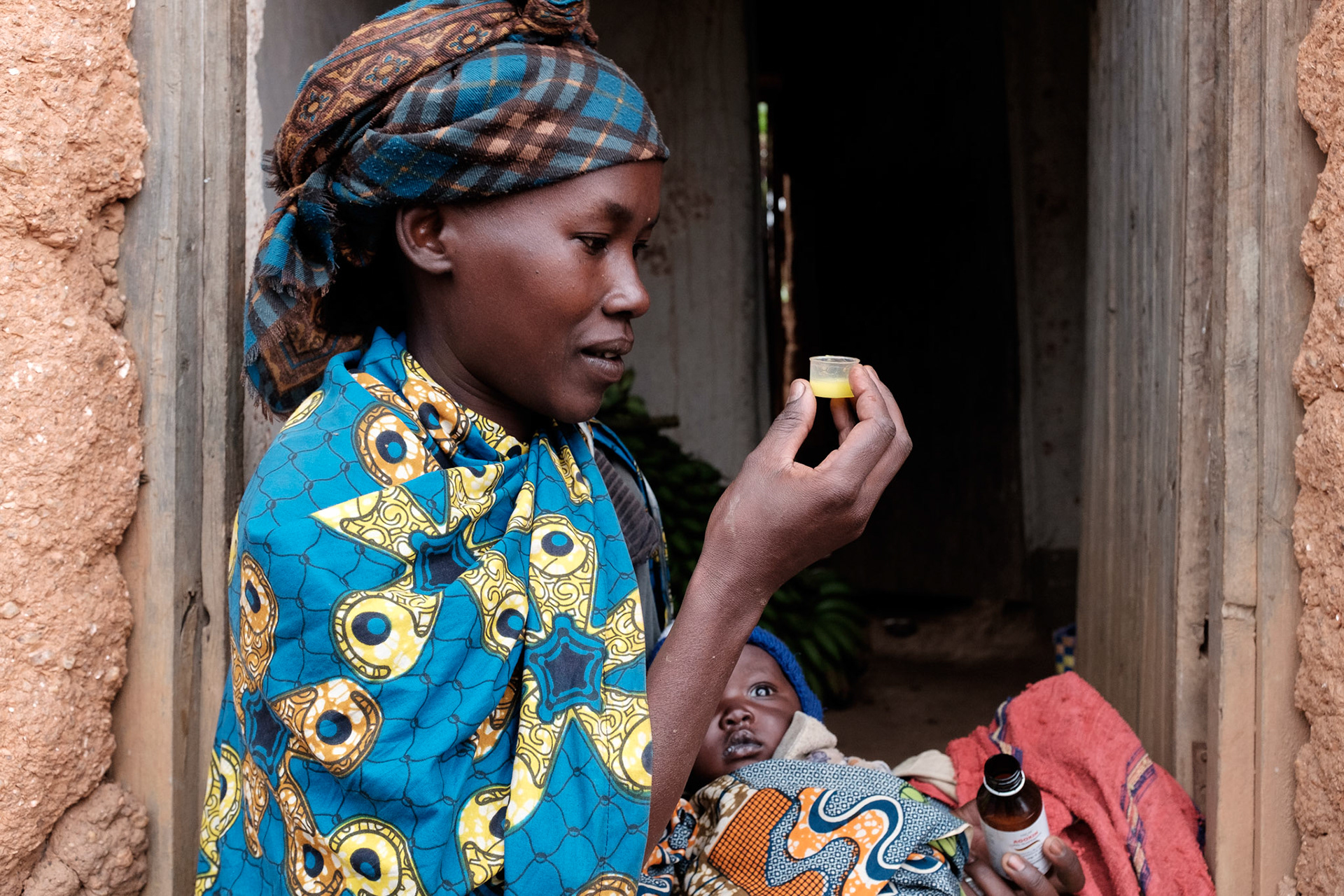 Immaculate' measures out medicine for her youngest daughter Clarisse, 2 months old.