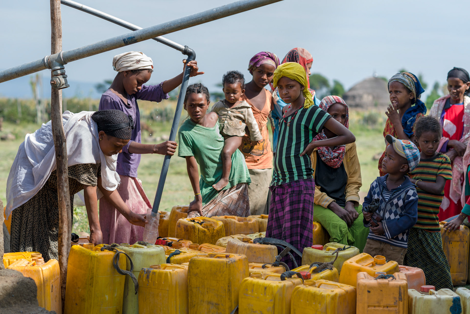 Women and children filling water cans from the Austrian Red Cross water tank.
The water tank collects rain water from the roof of the adjacent building. This water point saves the local people much time in collecting water.