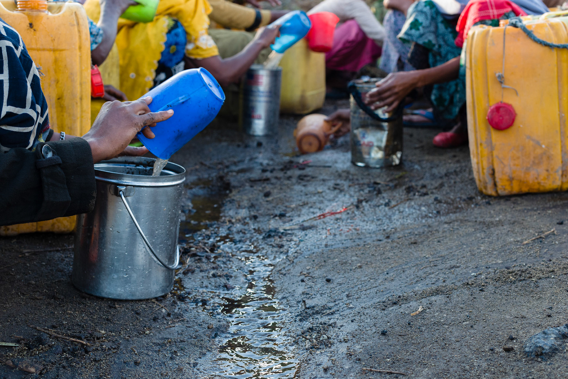When there is no easily accessible clean water source, women are forced to collect water where it can be found. These women in the Shalla region are collecting water running down a road.