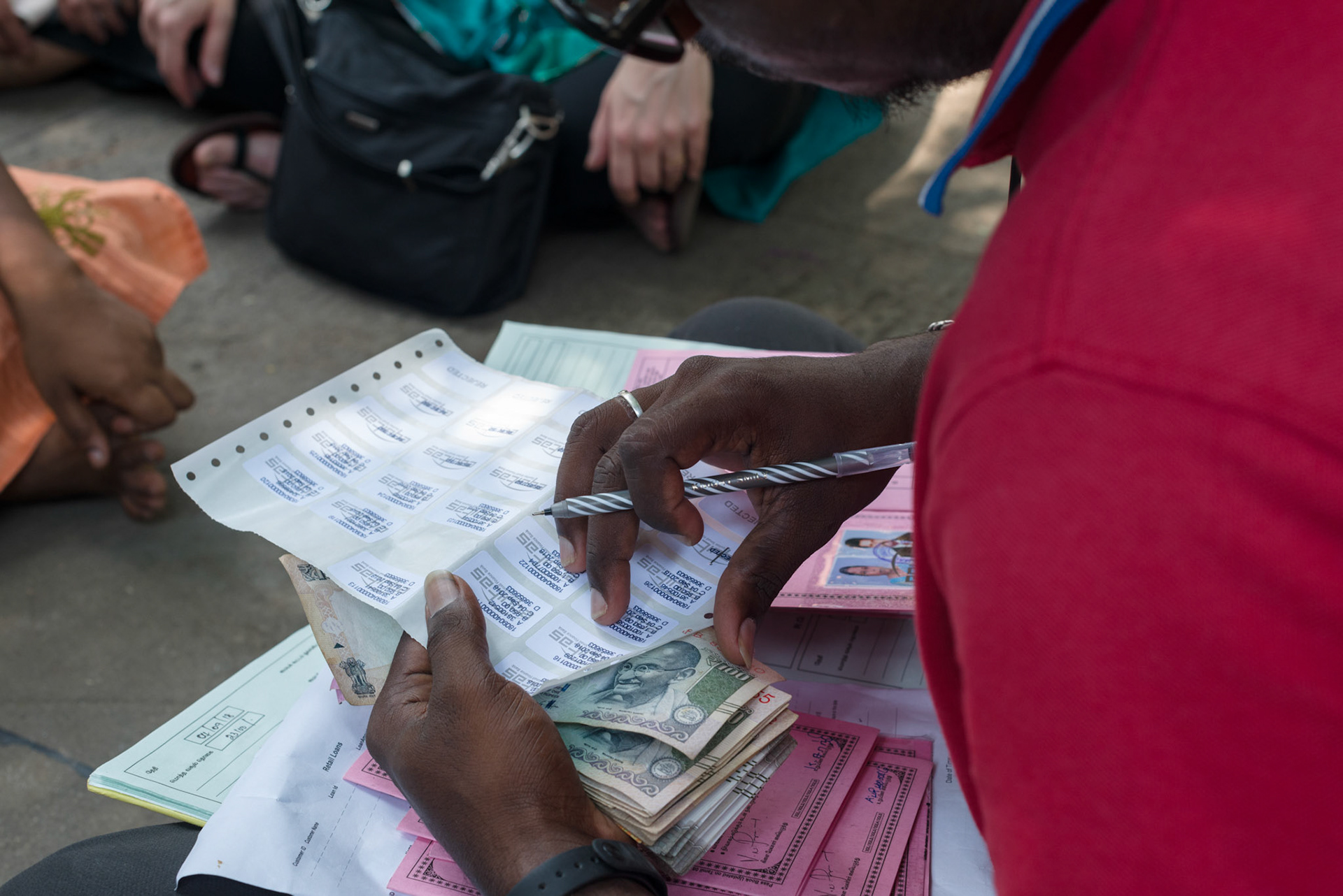 An Equitas field officer updates the women's savings books with stickers for the loan distribution.