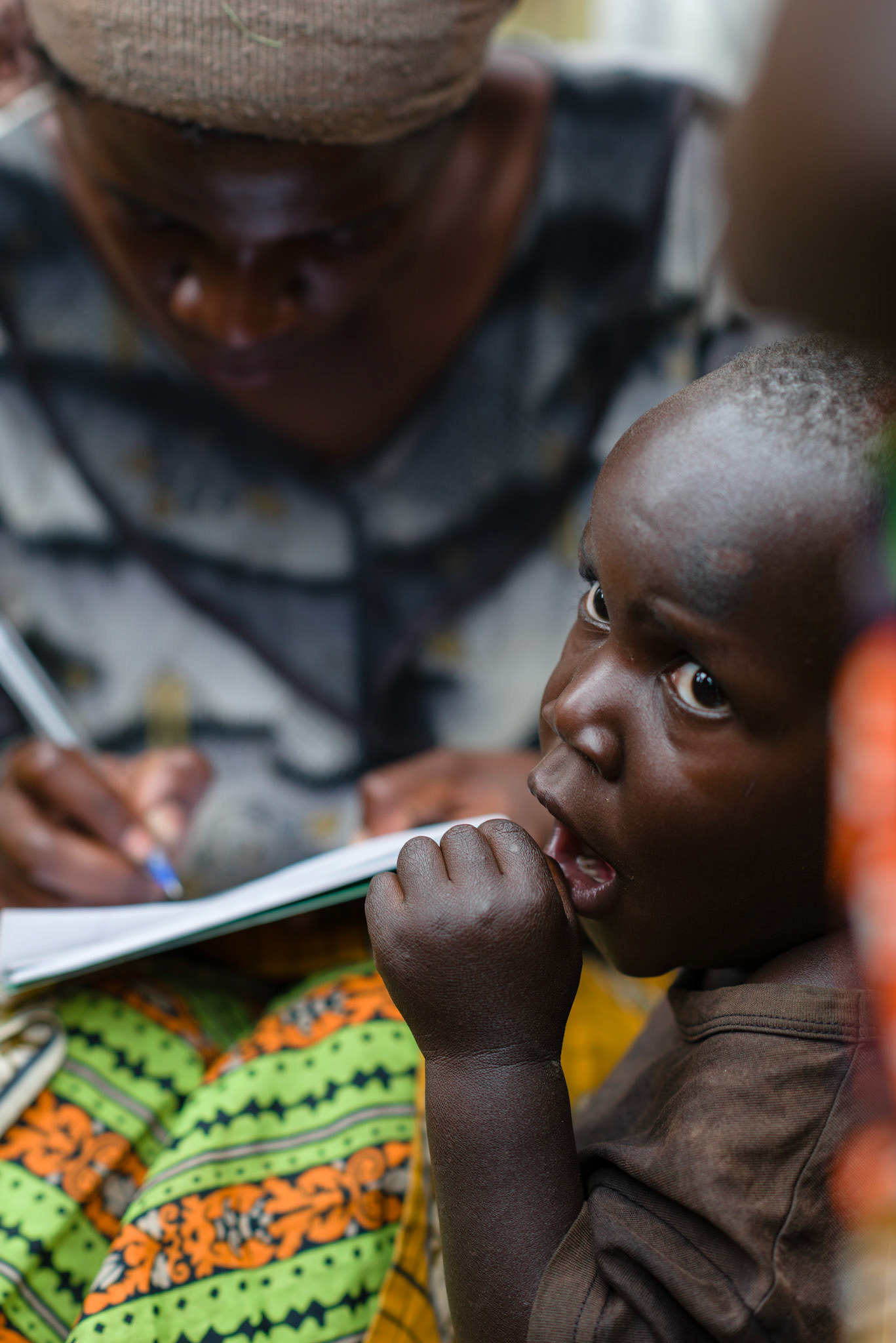A child yawns while his mother writes names of a new group's members.