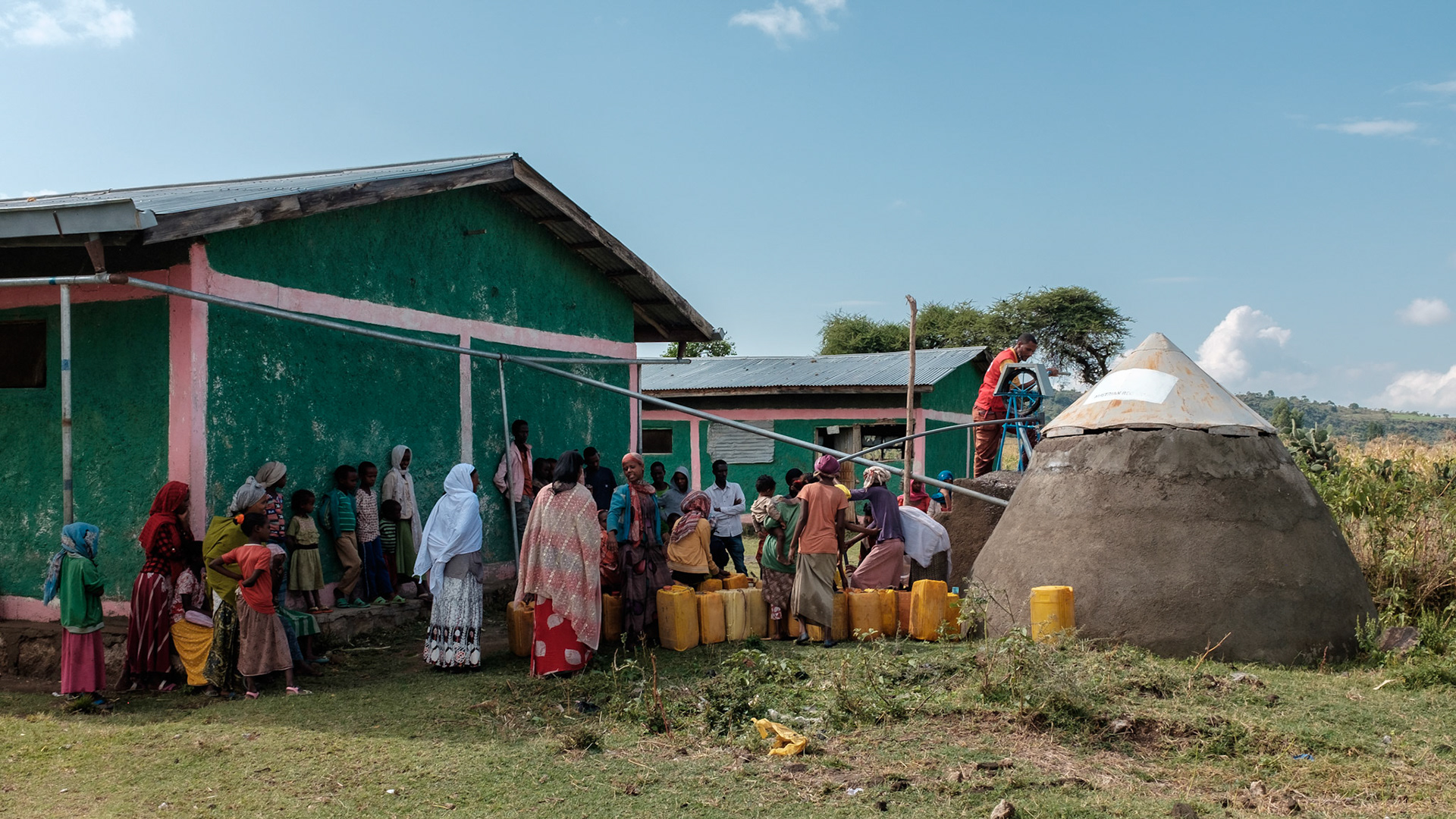 Women and children filling water cans from the Austrian Red Cross water tank.
The water tank collects rain water from the roof of the adjacent building. This water point saves the local people much time in collecting water.