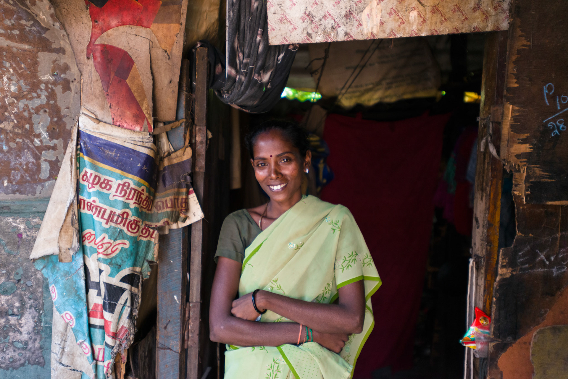 Deepa, 32, stand at the door of her shack. She works in a nearby cafe.