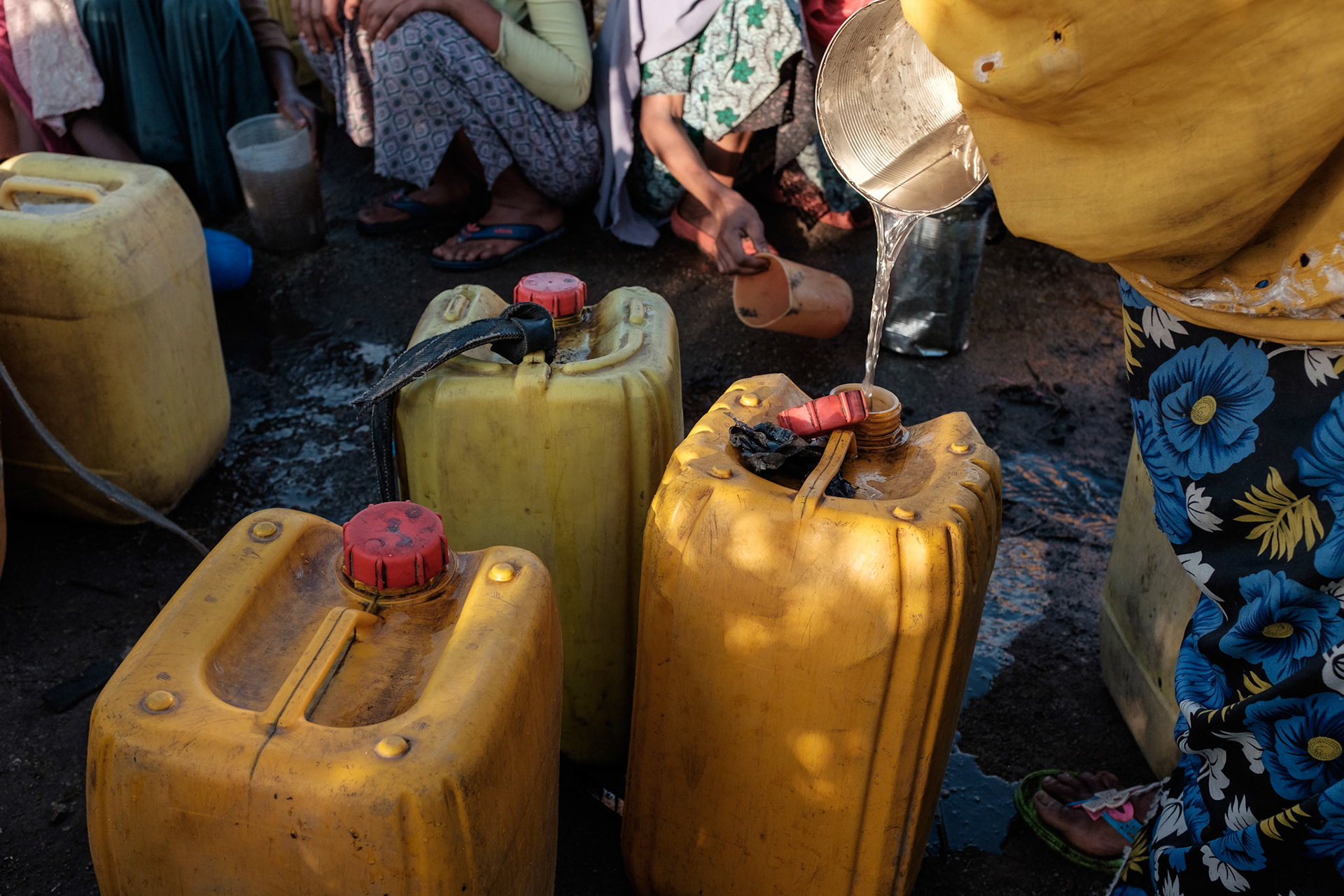 When there is no easily accessible clean water source, women are forced to collect water where it can be found. These women in the Shalla region are collecting water running down a road.