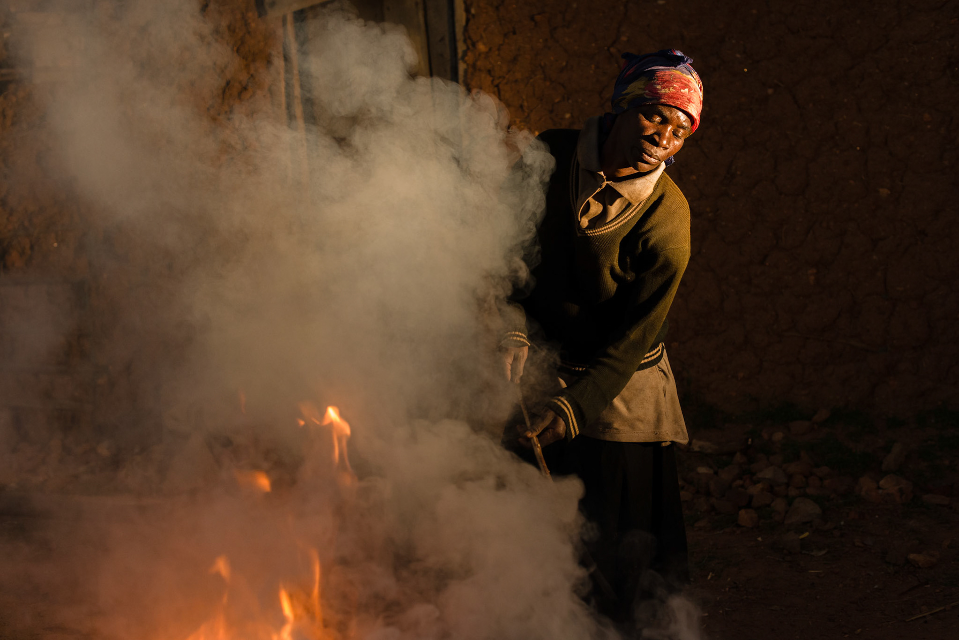 Philomene stokes the fire under the pots during firing.