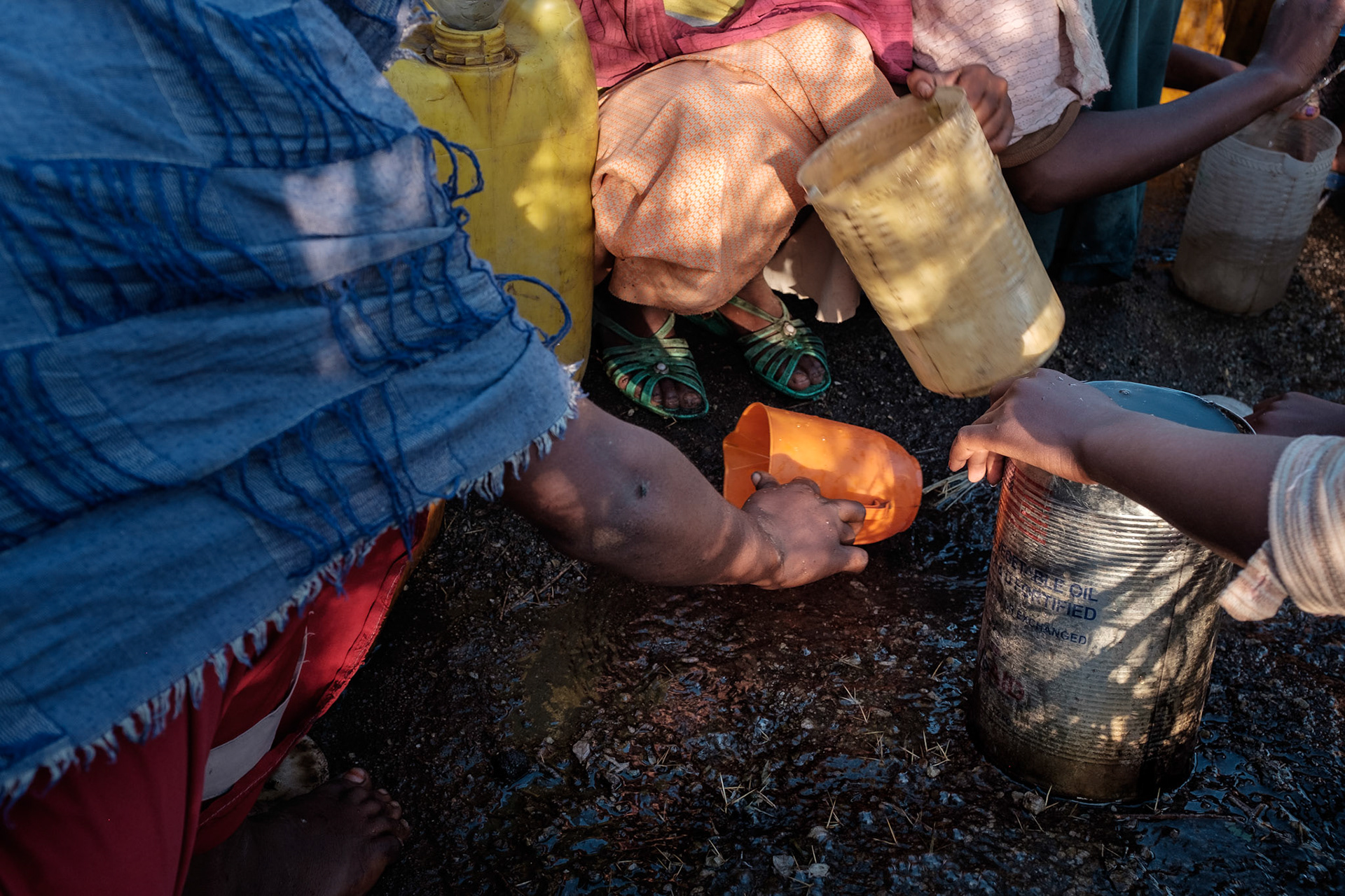 When there is no easily accessible clean water source, women are forced to collect water where it can be found. These women in the Shalla region are collecting water running down a road.
