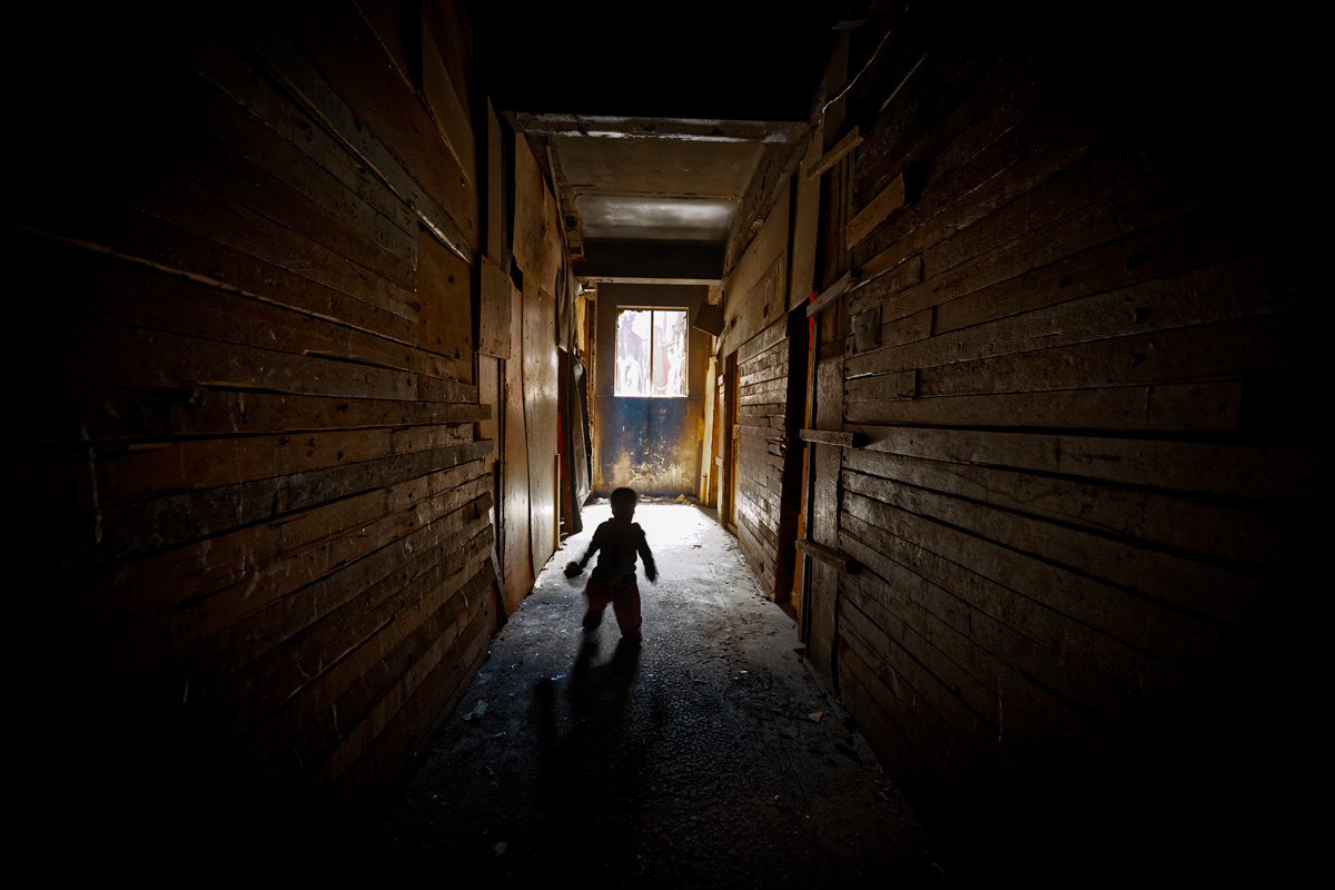 Lonely Child 2014 - 2016 Photographic Print Fine Art Cotton Rag A1. A toddler wonders the halls of a dark building, his mother was a heroine user and dealer. She explained in an interview how other residents abuse the boy when she is not around to show their distate towards her behaviour.