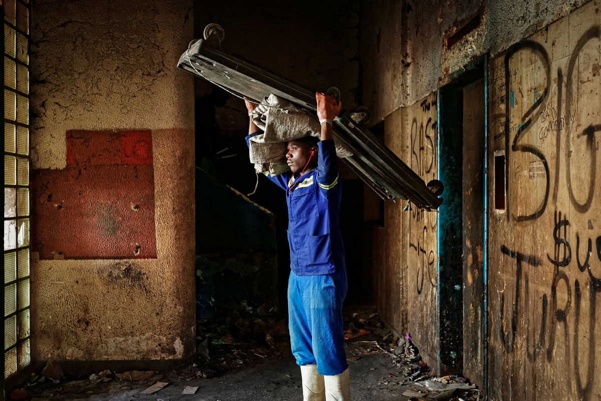 Trash Collector 2014 - 2016 210gsm Tecco Semi Matte, Face mounted 3mm perspex A1. A Zimbabwean man stands in the entrance of Dark City ready to begin a days recycling, many immigrants become recyclers in Johannesburg to make an income.