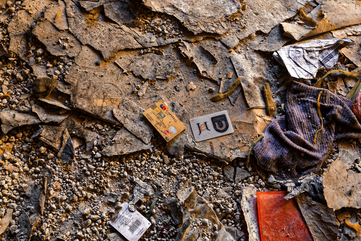 Jet, Thank You 2014 - 2016 Photographic Print UV , Lightbox 850mm x  850mm. A Capitec bank card and Jet loyalty card lie on the ground floor of Dark City as the leftovers of a mugging by Dark City criminals. Thank you written on the Jet card is a cynical comment when the card is no longer visualised in the retail space but rather in the ruins of a dark building.