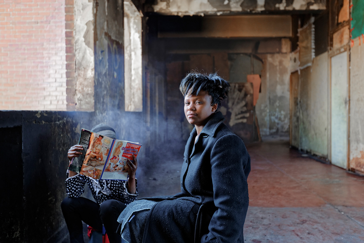 Reading A Porno 2014 - 2016 Photographic Print Fine Art Cotton Rag A0. Two women sit next to a fireplace on the sixth floor reading a porno magazine, the second woman chose to hide her identity in the photograph by lifting the magazine infront of her face.