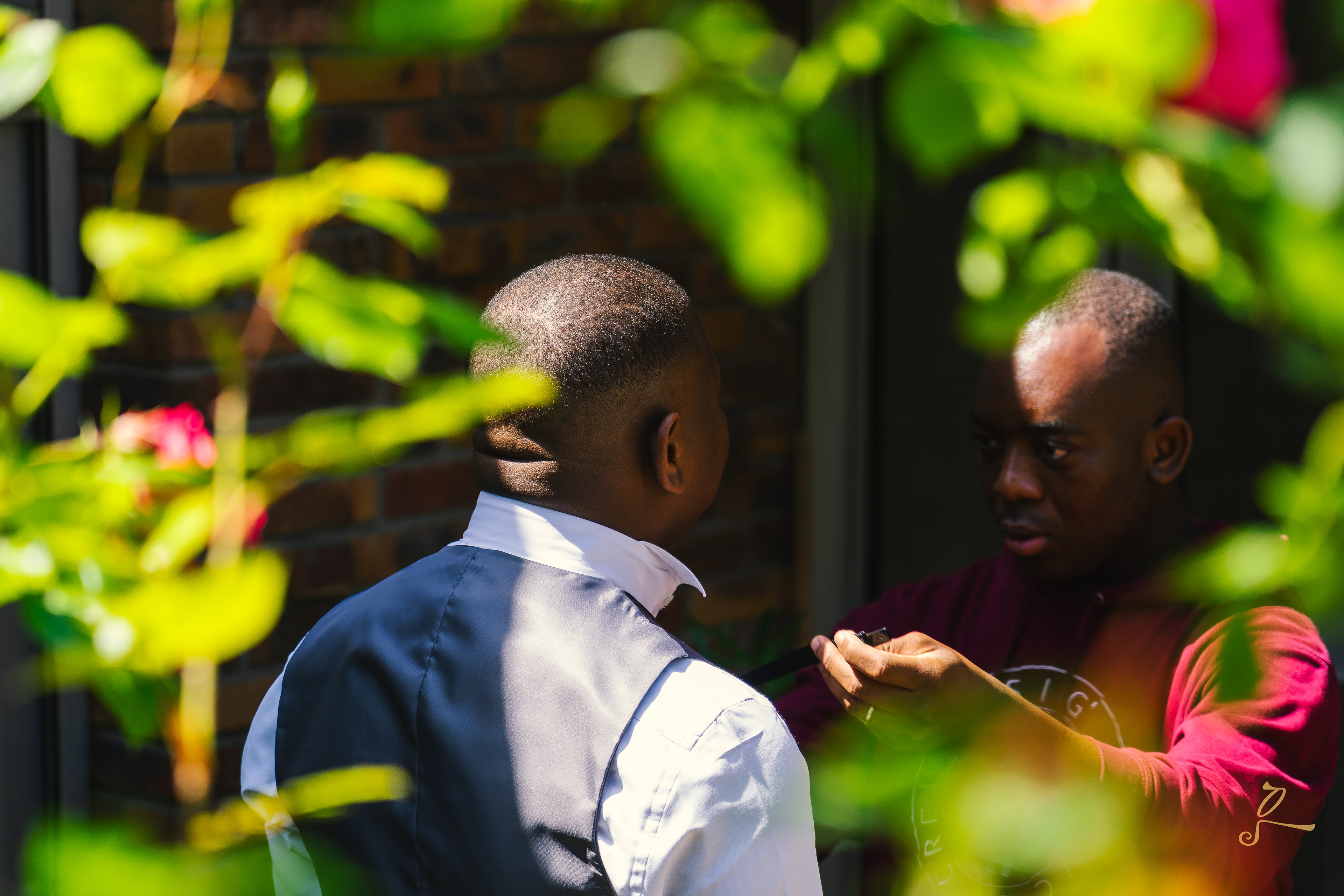 le marié se fait ajuster sa tenue dans la cour, styliste d'excellence Terbaro's style, noeud papillon en cuir, ceinture en cuir avec des motifs africains 