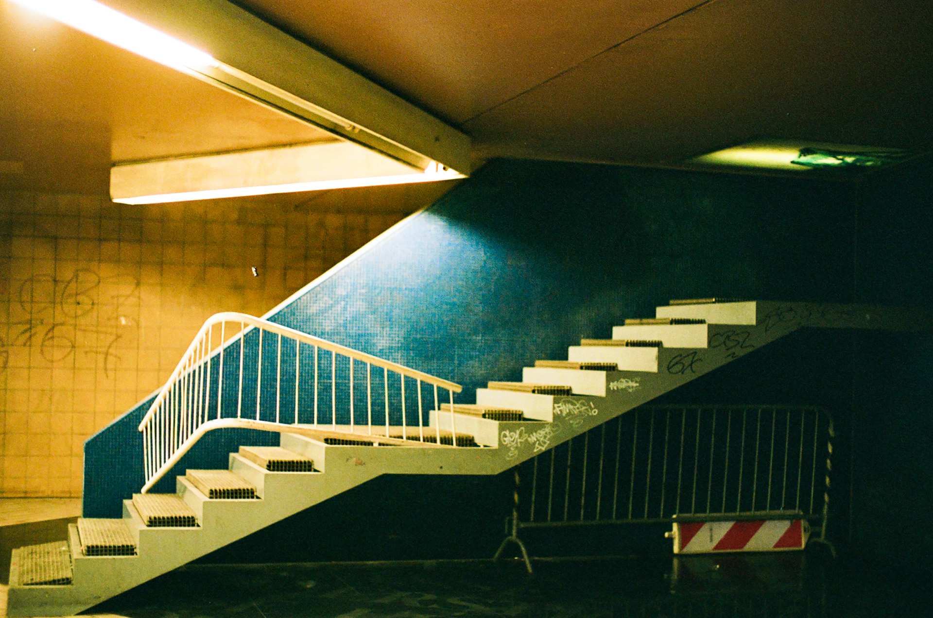 Hätte, hätte, Fahrradkette. Un dicho alemán que significa “debería haberlo hecho, pero no lo hice”; deja de pensar en eso, no se puede cambiar el pasado. Esta foto fue tomada en una estación del metro en Colonia, Alemania. Al principio no podía creer que en Alemania, el supuesto ejemplo del orden y la perfección, se pudiera cometer un error tan absurdo. Pensé en quien diseñó la escalera y me pregunté: ¿lo habrán despedido? Me llamó la atención que la gente seguía su camino desprevenidamente sin notar la inutilidad de la escalera. Esta escena me hizo pensar en un dicho que aprendí en ese viaje: “Hätte, hätte, Fahrradkette”. Quien sea que haya cometido el error, tendrá que decirse esta frase en algún momento y seguir hacia adelante. Después asumí que algo tan ilógico solo podía ser el producto de la imaginación de un artista. Ojalá algún día me puedan explicar qué pasó ahí.