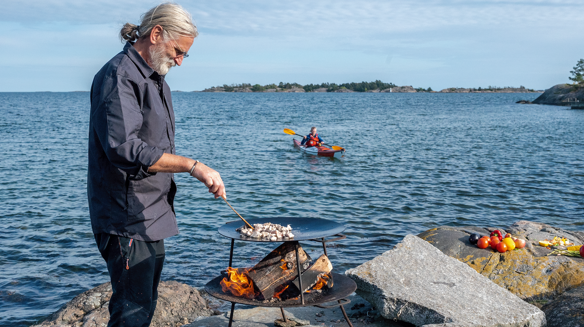 Erik Wallgren cooking chicken and John Savelid kayaking towards the campsite.