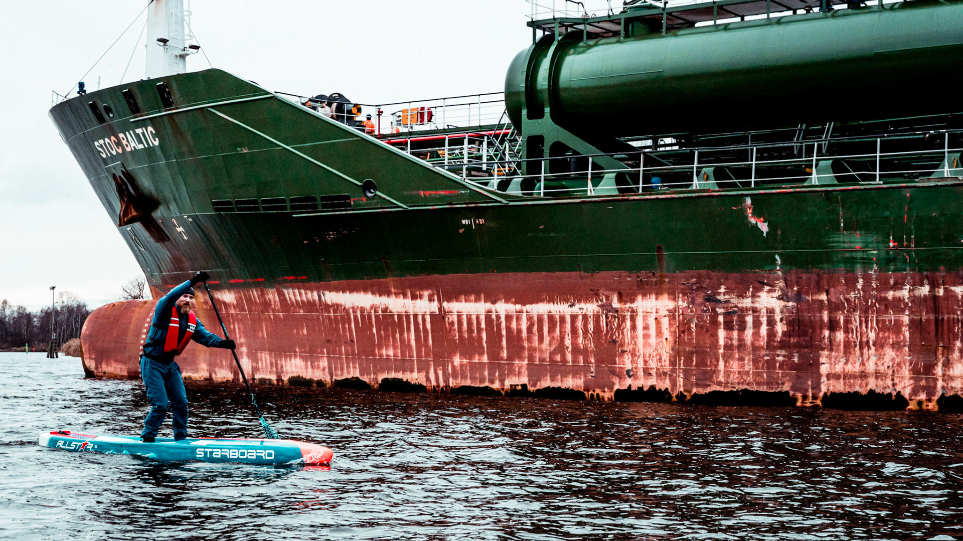 Johan Ulfving paddling in the canal next to an incoming cargo ship.