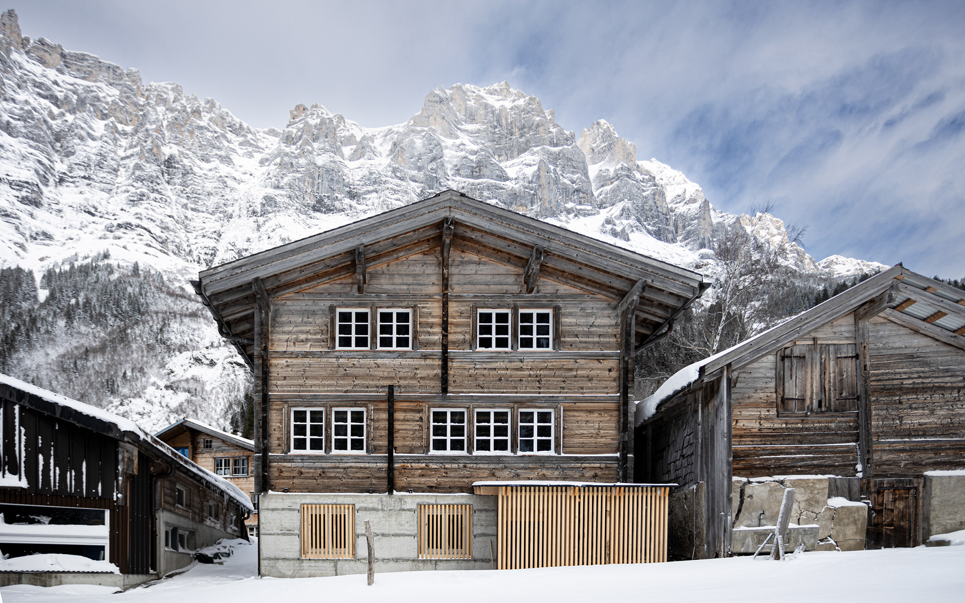 MKPHOTO, Architekturfotograf aus Aarau, Umgebautes Wohnhaus in Gadmen, Gesamtansicht Südfassade mit angrenzenden Stallungen und Bergkulisse im Hintergrund. 