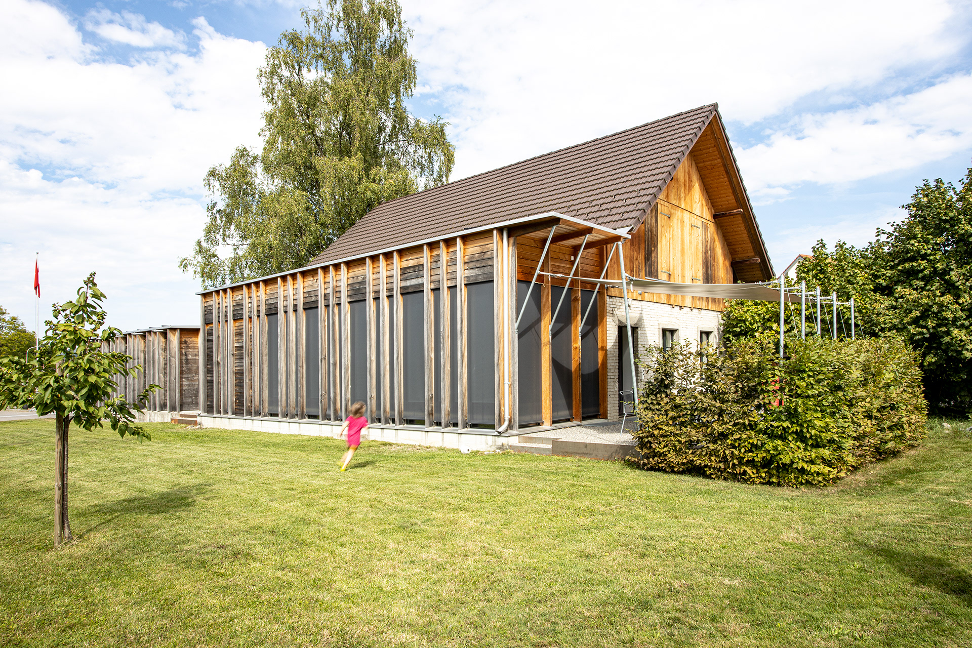 MKPHOTO, Architekturfotograf aus Aarau, Umgebaute Werkstatt in Gontenschwil, Südfassade mit Anbau und Gartensitzplatz.