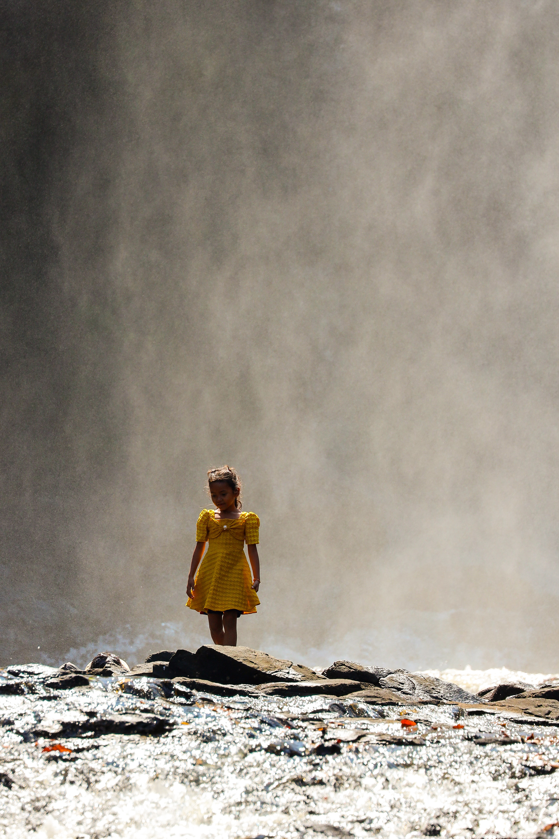 MKPHOTO, Landschaftsfotograf Schweiz, Mädchen mit gelbem Kleid vor einem Wasserfall in Kambodscha. 